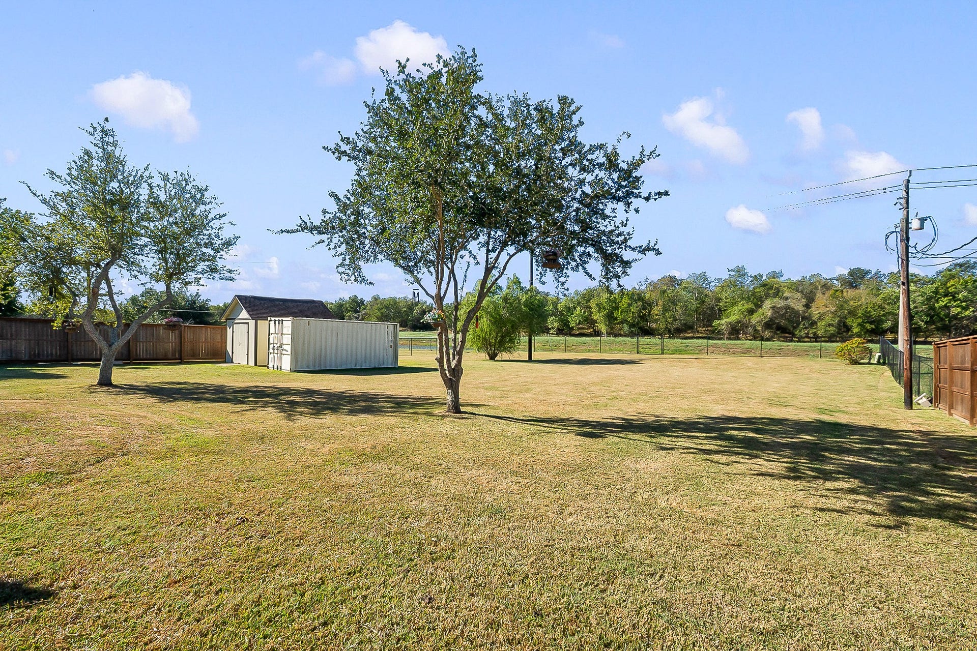 928 Oleander Street, Lake Jackson, TX 77566 Expansive backyard with lush green lawn, mature trees, and ample space for outdoor activities, complemented by a privacy fence that backs up to the view of the water.