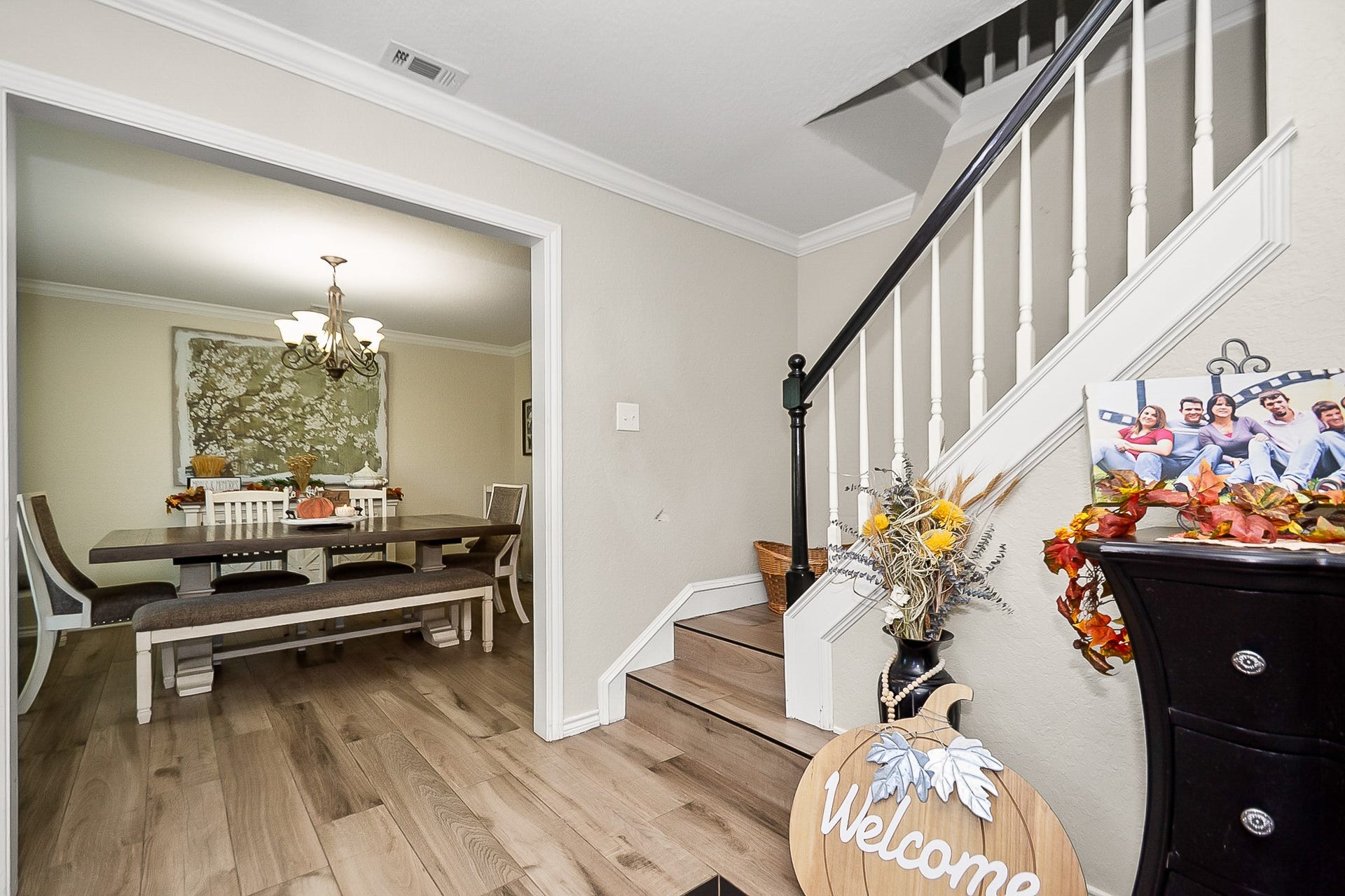 928 Oleander Street, Lake Jackson, TX 77566 Inviting entryway with a charming staircase leads to a cozy dining area, featuring elegant lighting and fits a large wooden table perfect for gatherings.