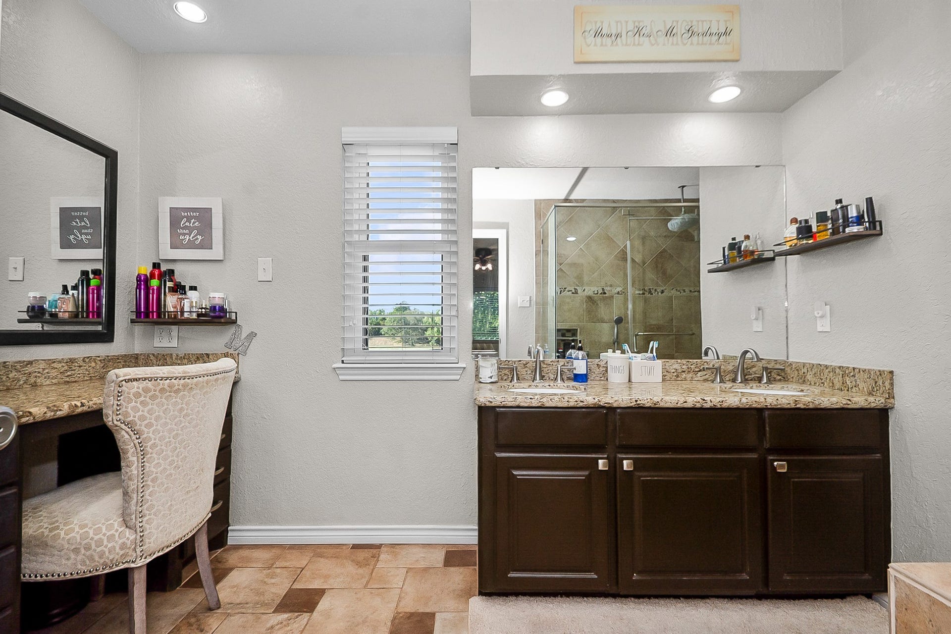 928 Oleander Street, Lake Jackson, TX 77566 Elegant bathroom featuring dual sinks with granite countertops, a spacious vanity area, and a large mirror. Natural light flows through the window, highlighting the stylish tile flooring and modern fixtures.