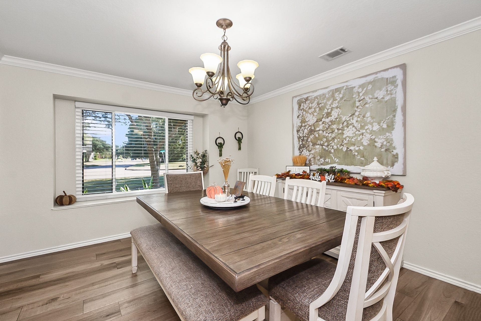 928 Oleander Street, Lake Jackson, TX 77566 Bright and inviting dining room featuring a large window, elegant chandelier, and stylish wood look flooring, perfect for hosting gatherings.