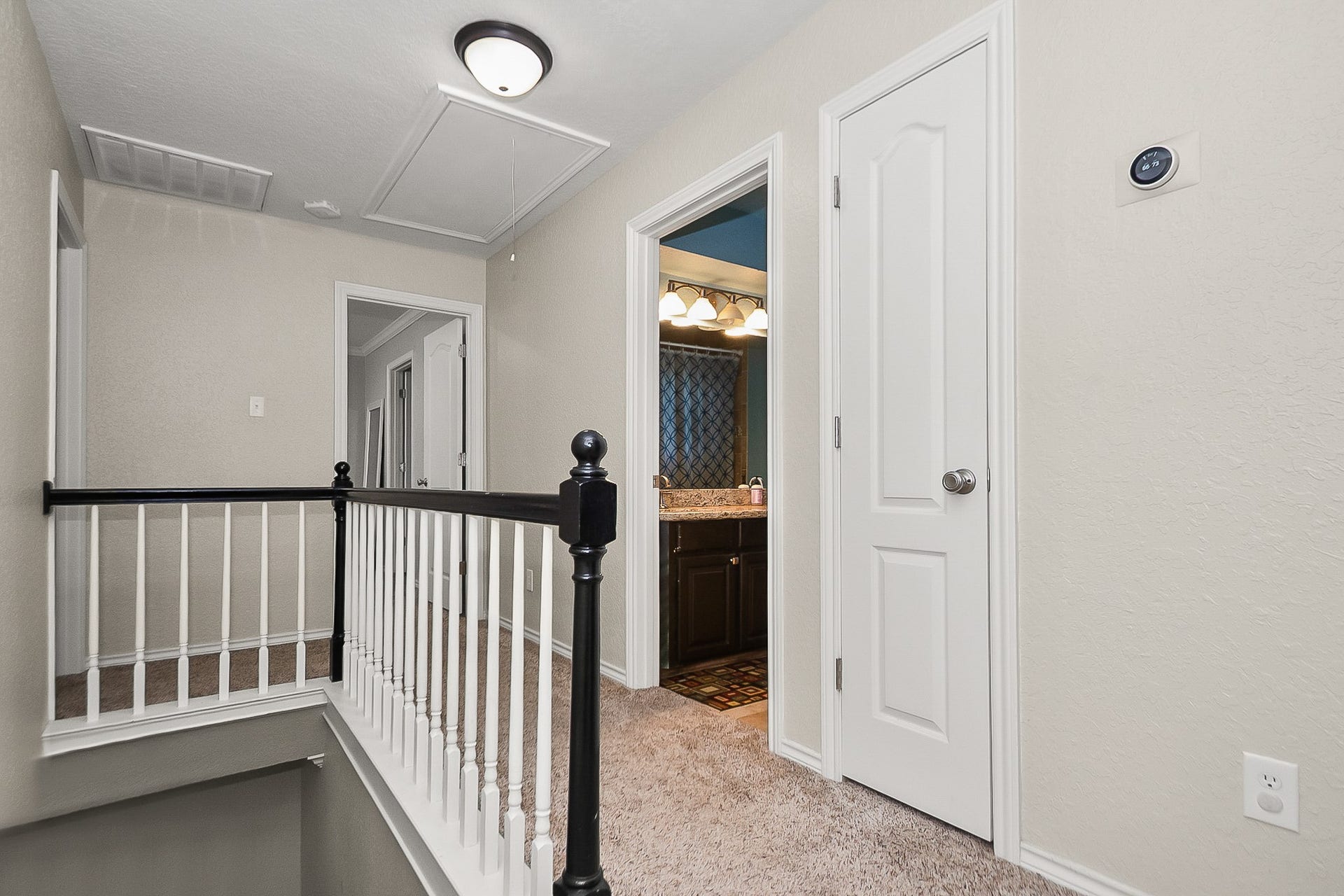 928 Oleander Street, Lake Jackson, TX 77566 Bright and inviting upstairs landing with plush carpeting and elegant railing, leading to a well-appointed bathroom featuring a granite countertop.