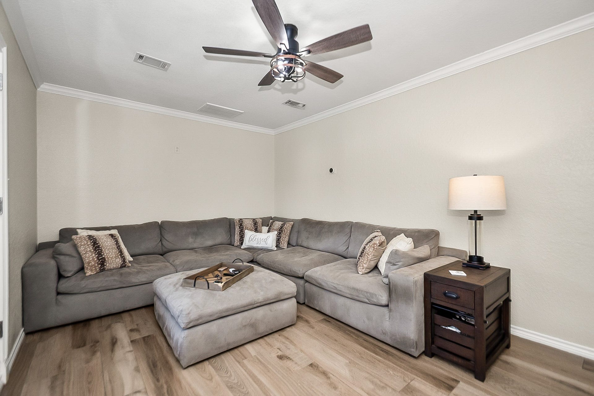 928 Oleander Street, Lake Jackson, TX 77566 Cozy living area featuring a spacious L-shaped sectional sofa, warm wood like flooring, and a ceiling fan for comfort and style.