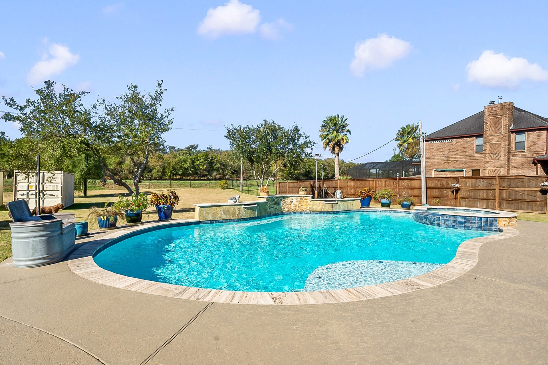 928 Oleander Street, Lake Jackson, TX 77566 Experience outdoor luxury with a sparkling heated pool surrounded by lush landscaping, ample patio space, and a charming stone accent wall. Perfect for relaxation and entertaining.