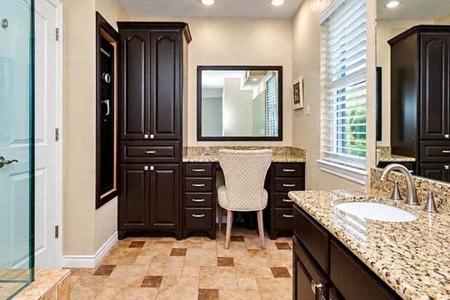 928 Oleander Street, Lake Jackson, TX 77566 Elegant bathroom featuring rich dark wood cabinetry, granite countertops, and a cozy vanity area, complemented by warm tile flooring and abundant natural light.