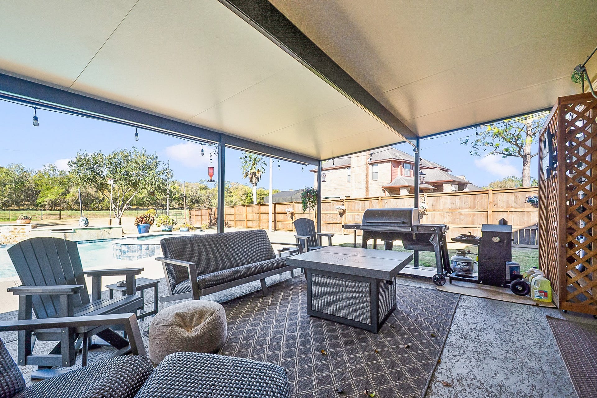 928 Oleander Street, Lake Jackson, TX 77566 Enjoy outdoor living in this spacious 988 sq. ft. covered patio featuring comfortable seating, a grill for barbecues, and a view of the inviting pool, perfect for relaxation and entertaining.
