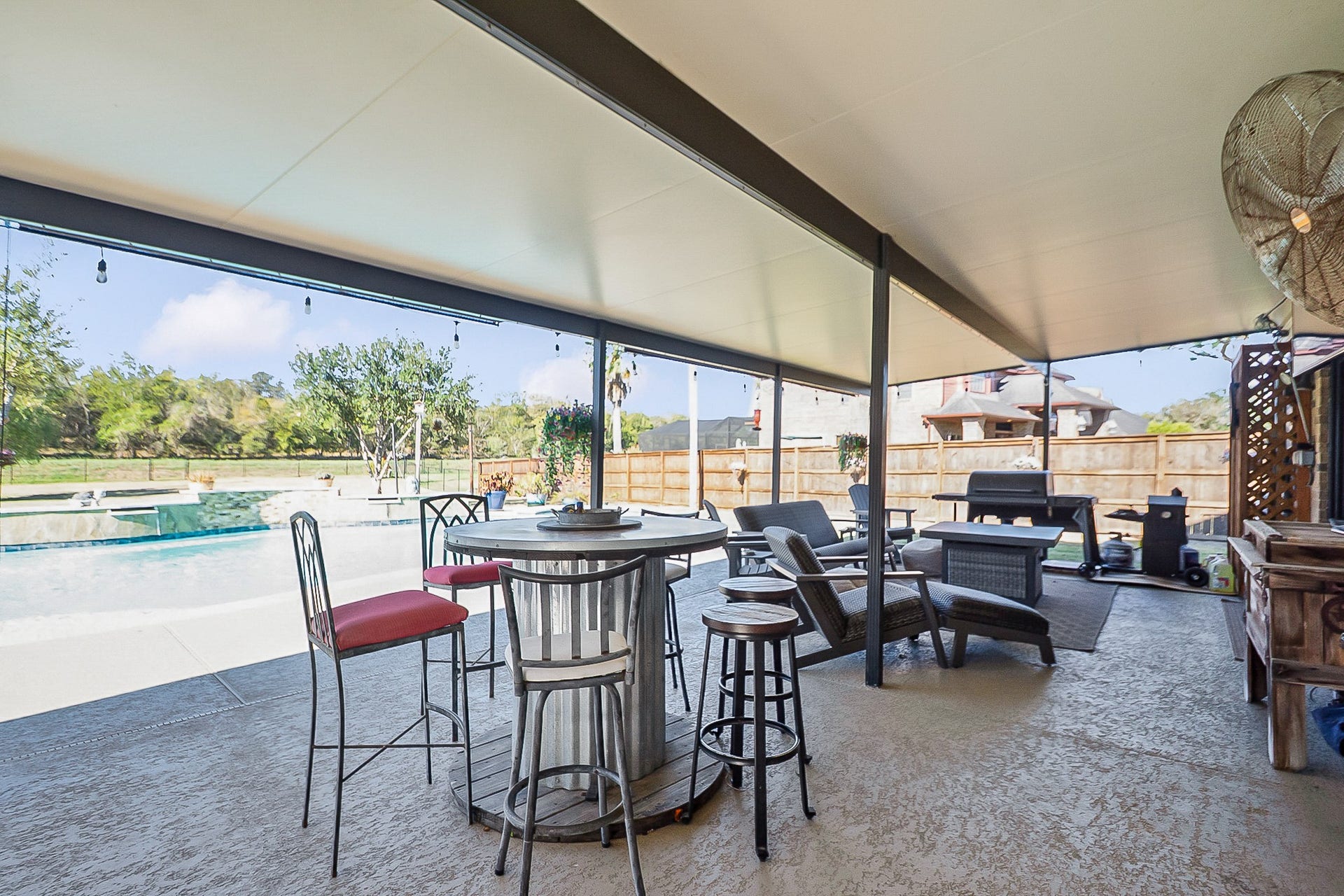 928 Oleander Street, Lake Jackson, TX 77566 Spacious 988 sq. ft. Covered patio with seating and dining area overlooks a sparkling pool, perfect for outdoor entertaining.