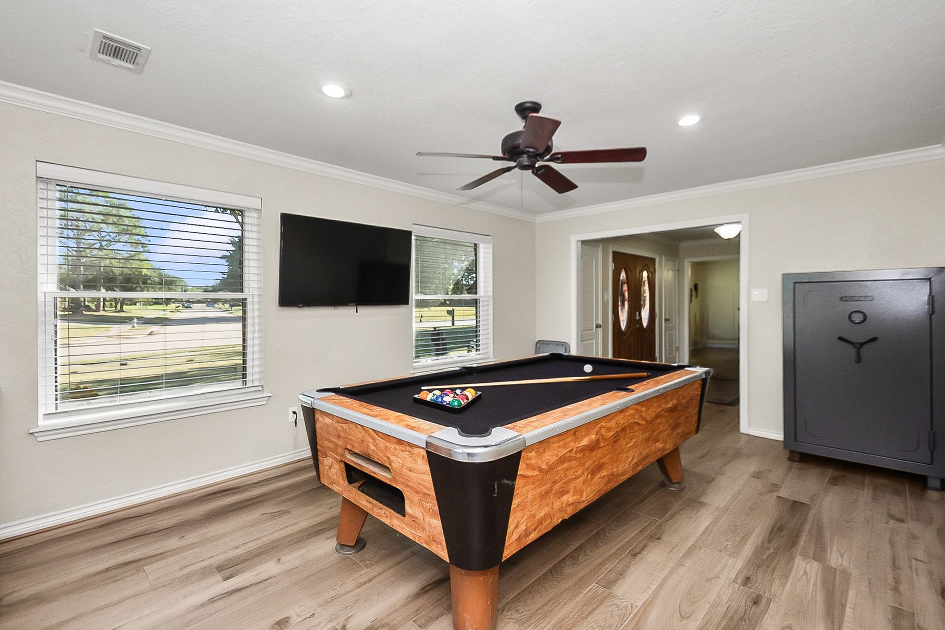 928 Oleander Street, Lake Jackson, TX 77566 Spacious game room featuring a stylish pool table, sleek wood look floors, and ample natural light, perfect for entertainment and relaxation. can also be used as a formal Living room or you decide.
