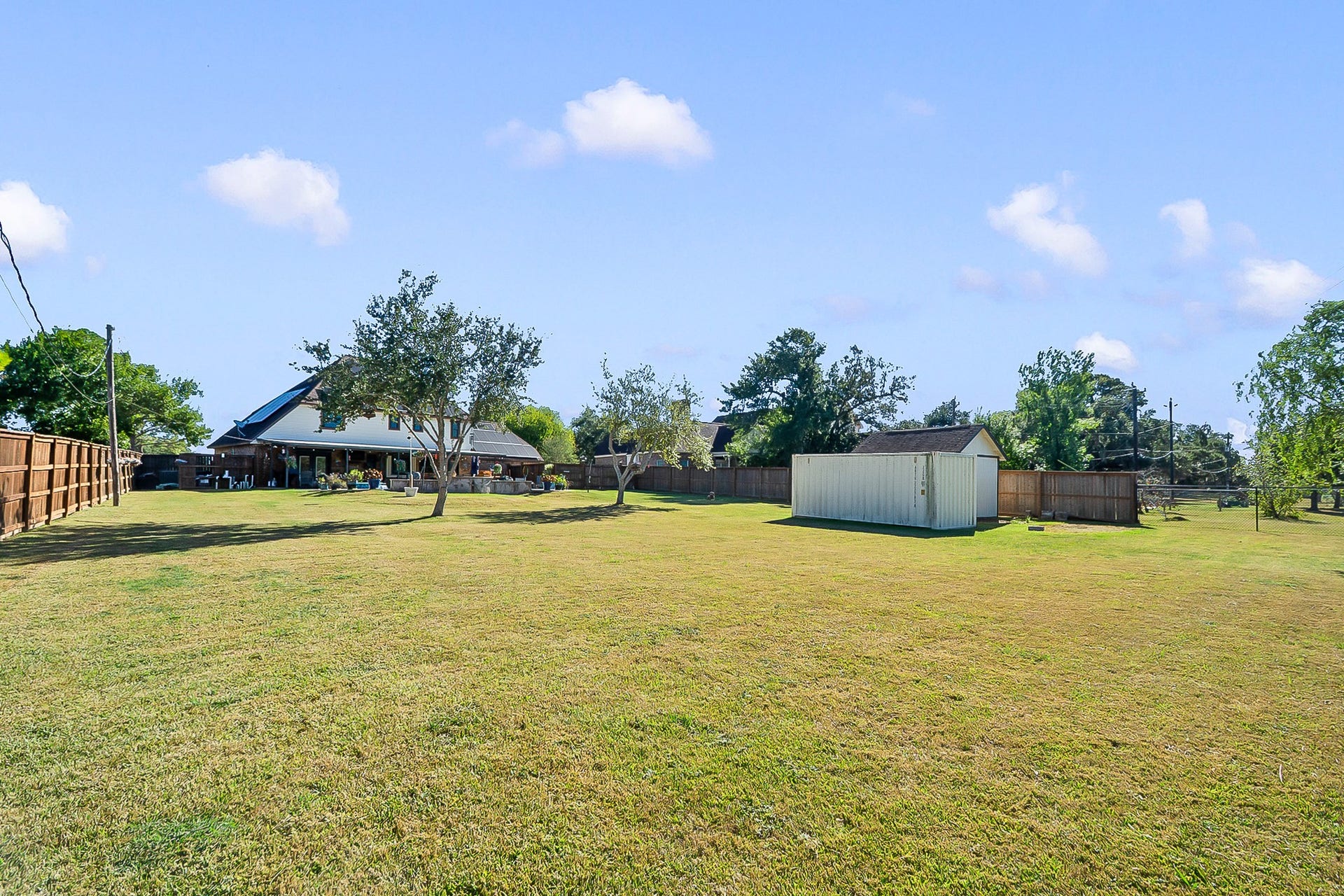 928 Oleander Street, Lake Jackson, TX 77566 Expansive backyard with lush green lawn, mature trees, and a storage shed, perfect for outdoor activities.