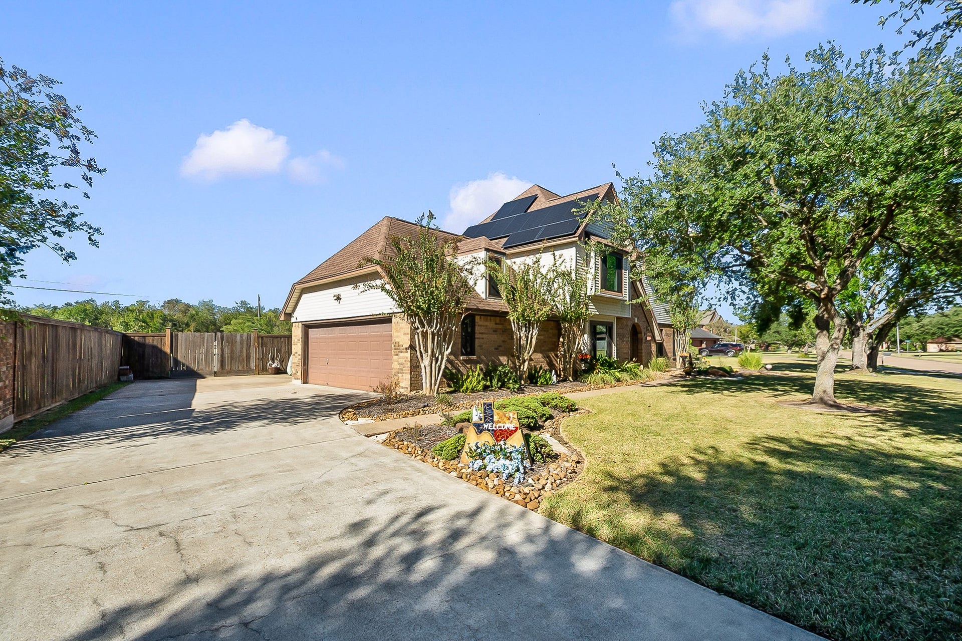 928 Oleander Street, Lake Jackson, TX 77566 Spacious two-story home with paid off solar panels, featuring a large driveway, attached garage, and beautifully landscaped yard with mature trees.