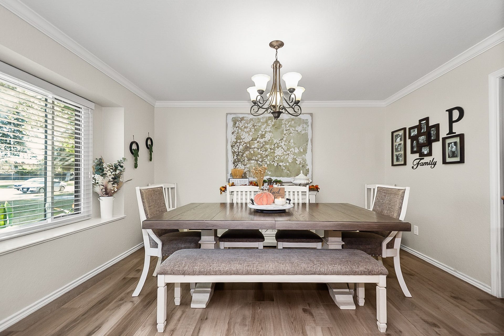 928 Oleander Street, Lake Jackson, TX 77566 Charming dining room with elegant wood like flooring, a large window offering abundant natural light, and a stylish chandelier above a spacious table with ample seating for gatherings.