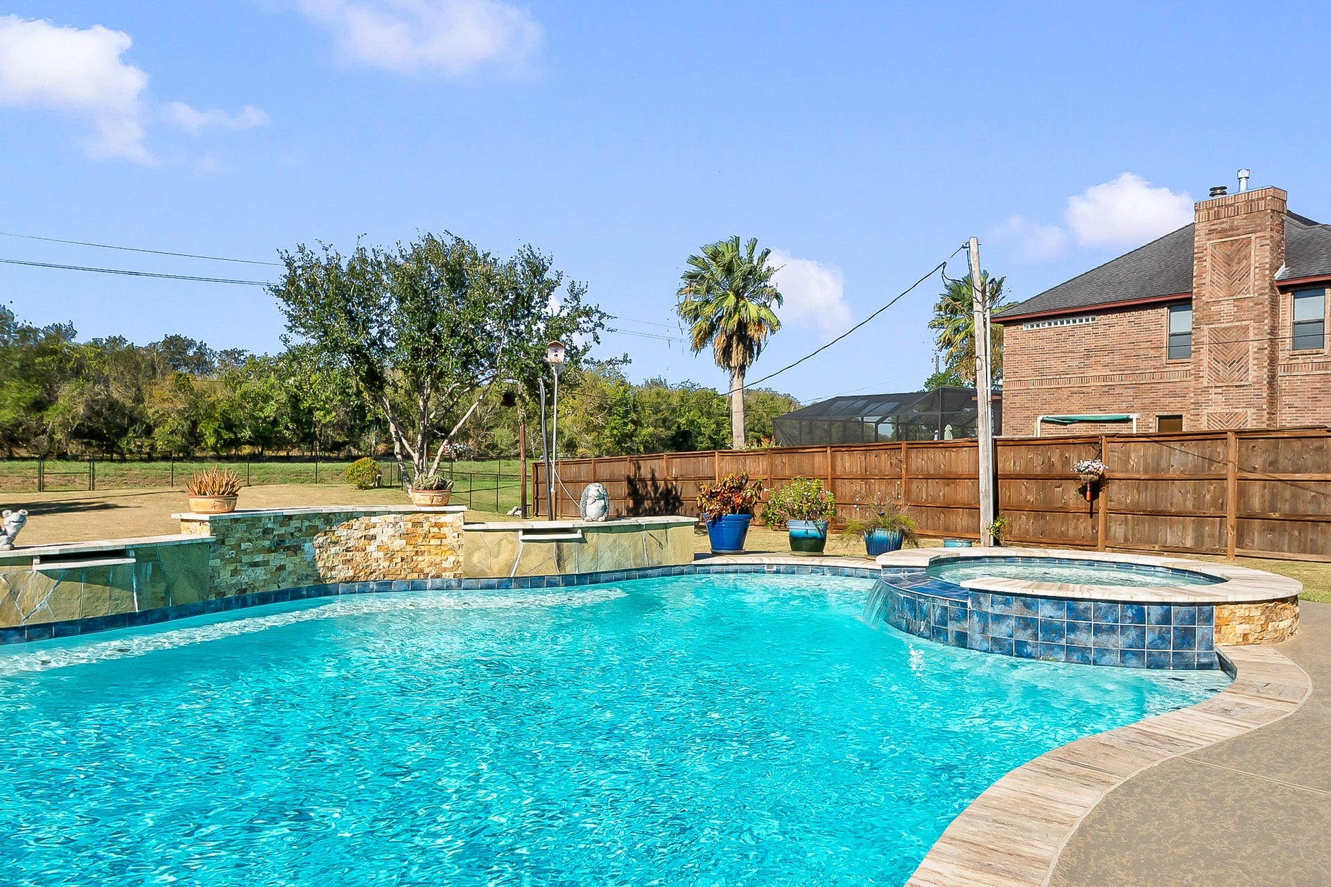 928 Oleander Street, Lake Jackson, TX 77566 Stunning backyard oasis featuring a sparkling heated pool and spa, surrounded by lush landscaping and a privacy fence, perfect for relaxation and entertaining.
