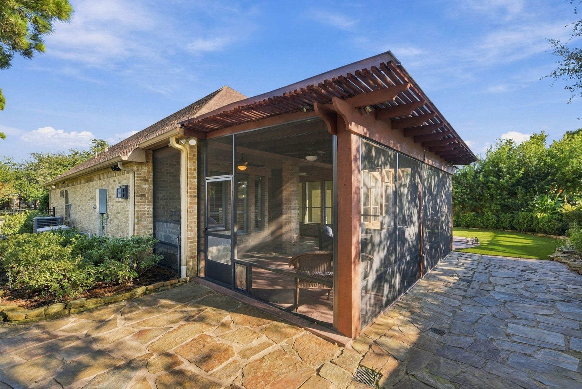 The stone patio and lush greenery create a serene backyard retreat.