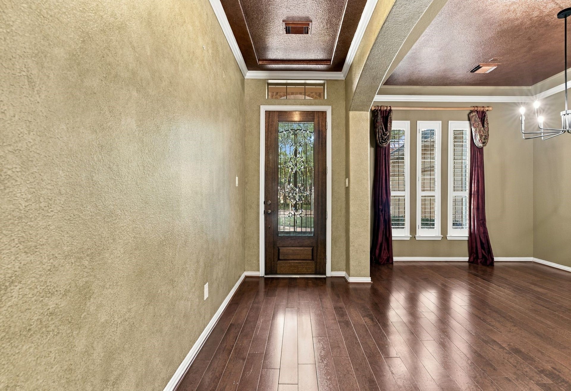 Elegant entryway with rich wood flooring, a decorative glass front door.