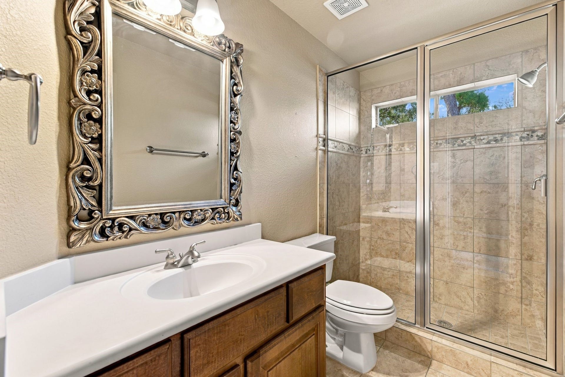 Elegant bathroom secondary bedroom featuring a beautifully mirror, sleek vanity, and a spacious glass-enclosed shower.
