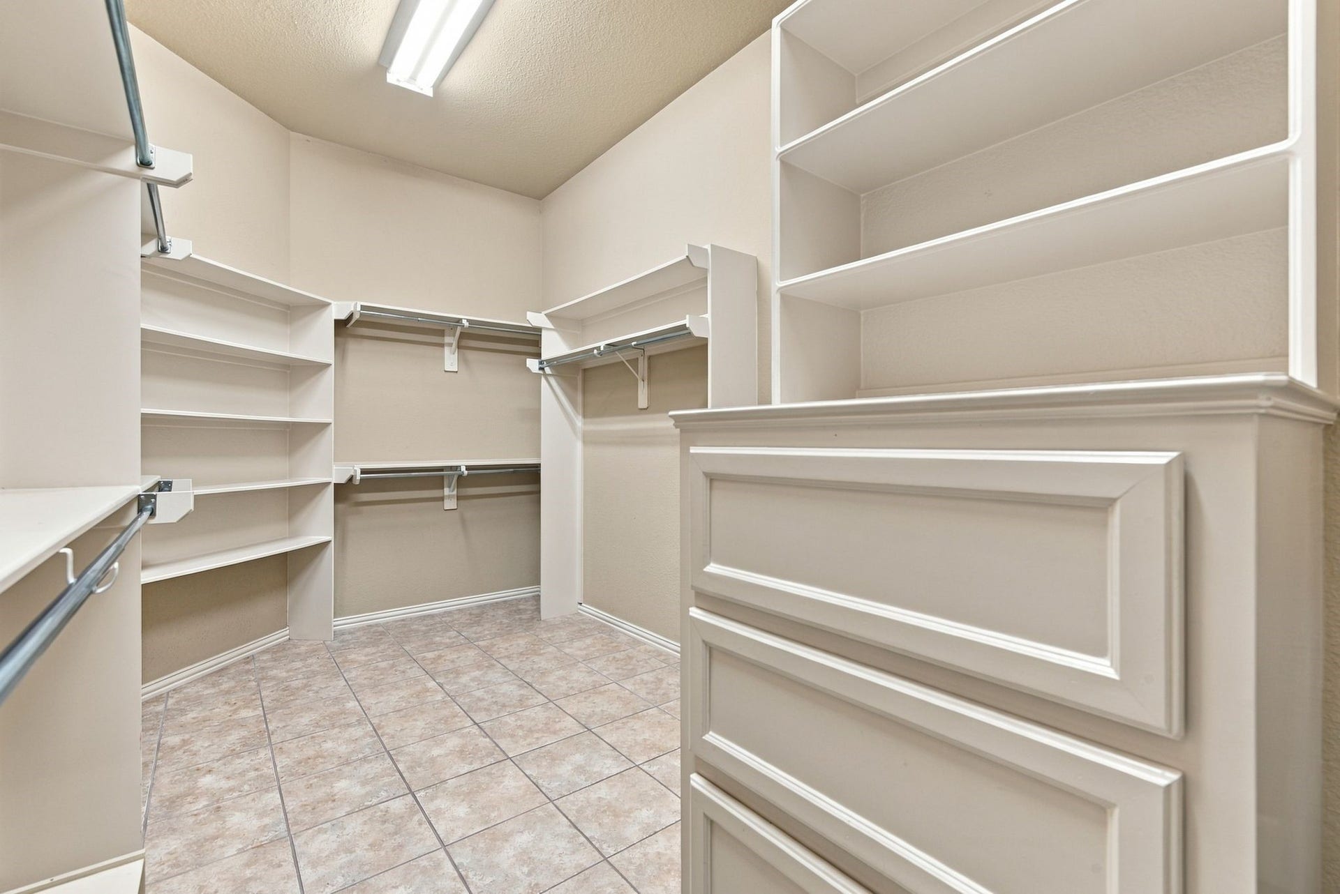 Spacious walk-in closet featuring ample shelving, hanging rods, and built-in drawers for organized storage.