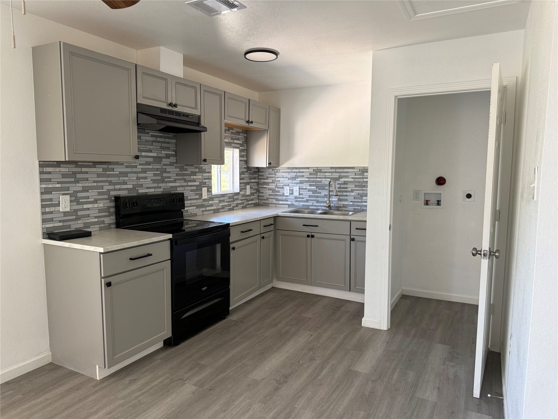 316 20th Street, #1, San Leon, TX 77539 Updated kitchen with gray shaker cabinets, mosaic tile backsplash and an electric range.
