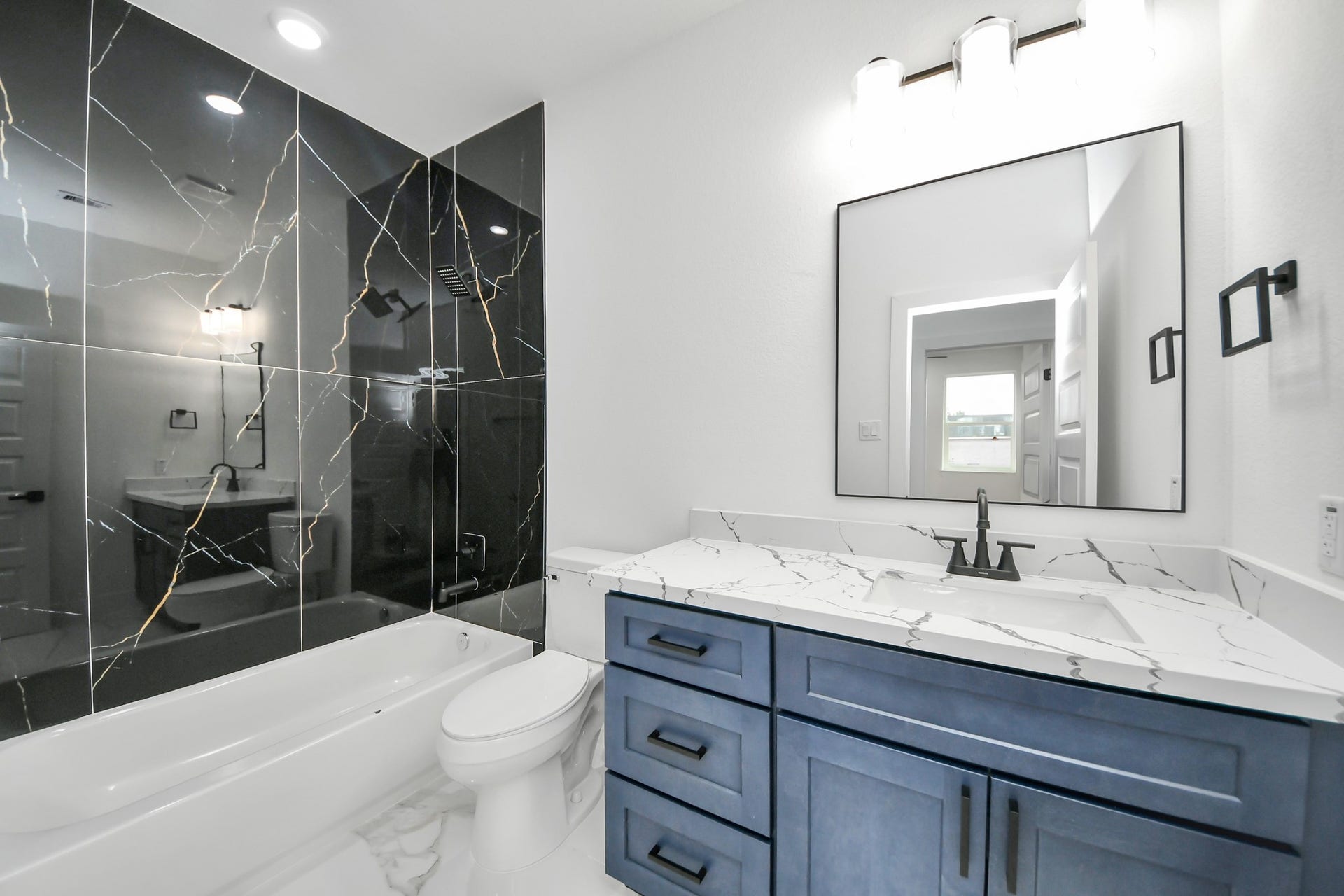 6707 Knox Street, Houston, TX 77091 Elegant bathroom featuring a luxurious black marble shower wall, sleek vanity with a marble countertop, and modern fixtures for a sophisticated touch.