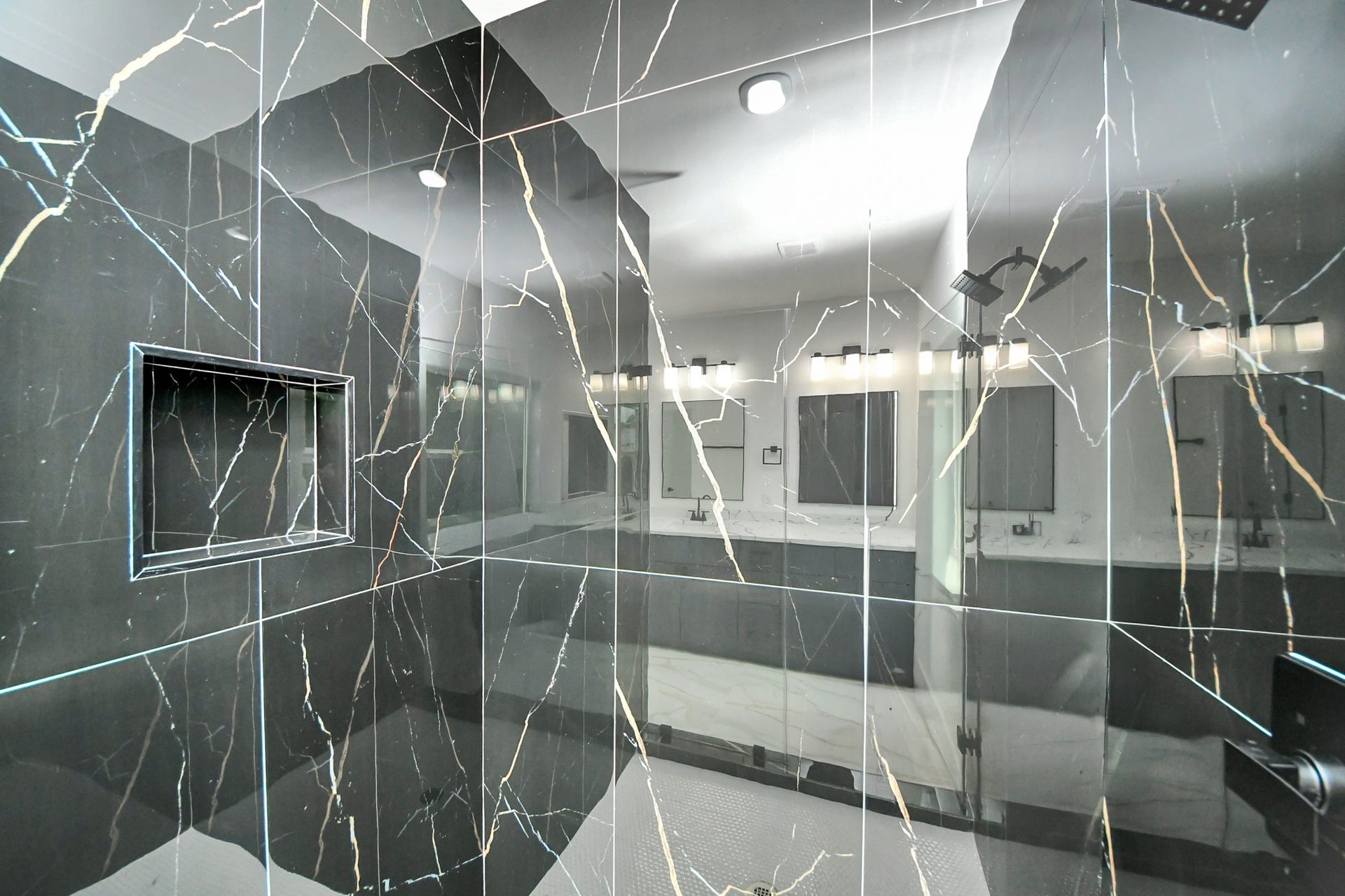 6707 Knox Street, Houston, TX 77091 Luxurious bathroom featuring a sleek, black marble shower with elegant veining and a built-in niche for convenience.