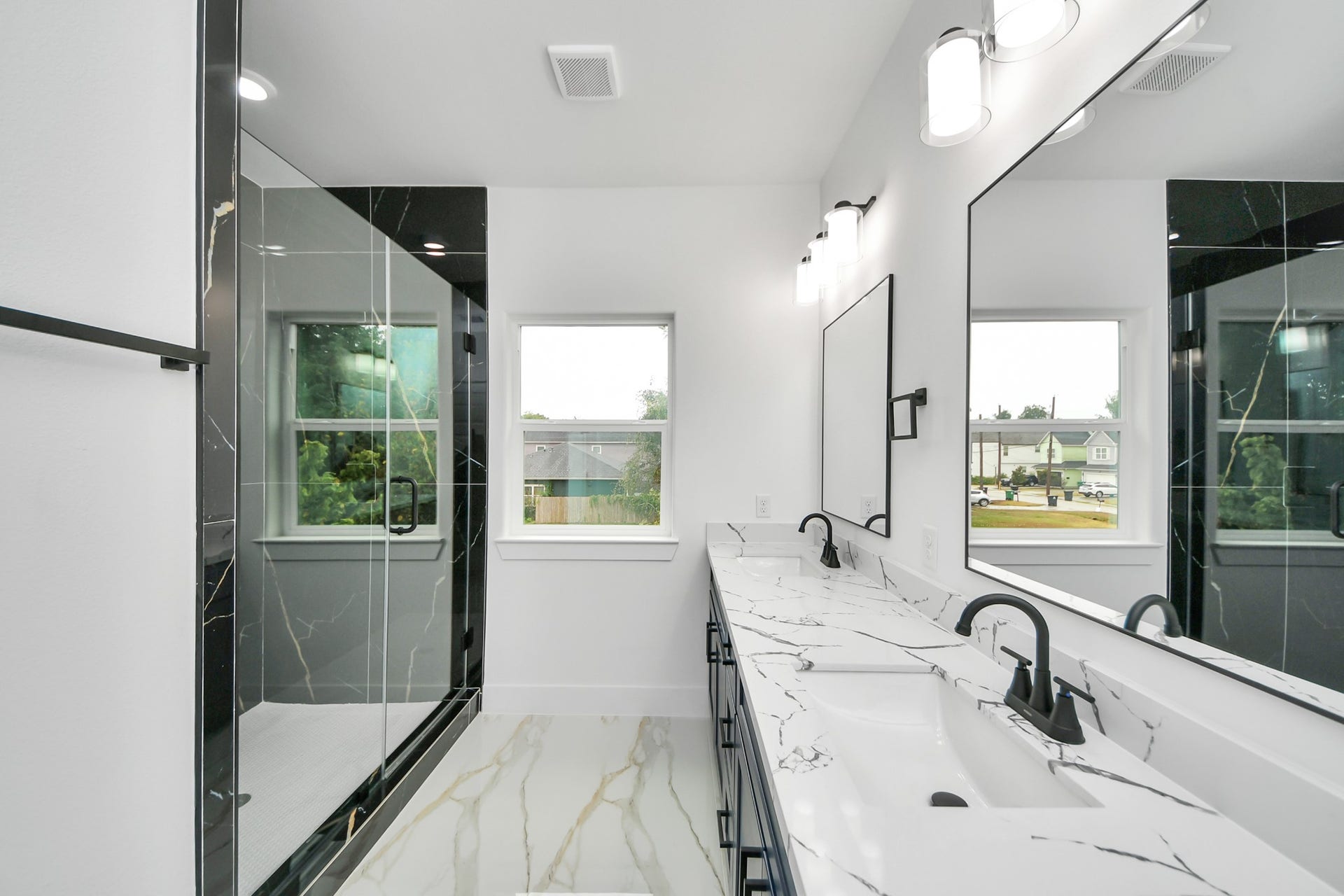 6707 Knox Street, Houston, TX 77091 Elegant bathroom featuring a spacious dual-sink vanity with sleek black fixtures and luxurious marble countertops, complemented by a modern glass-enclosed shower.