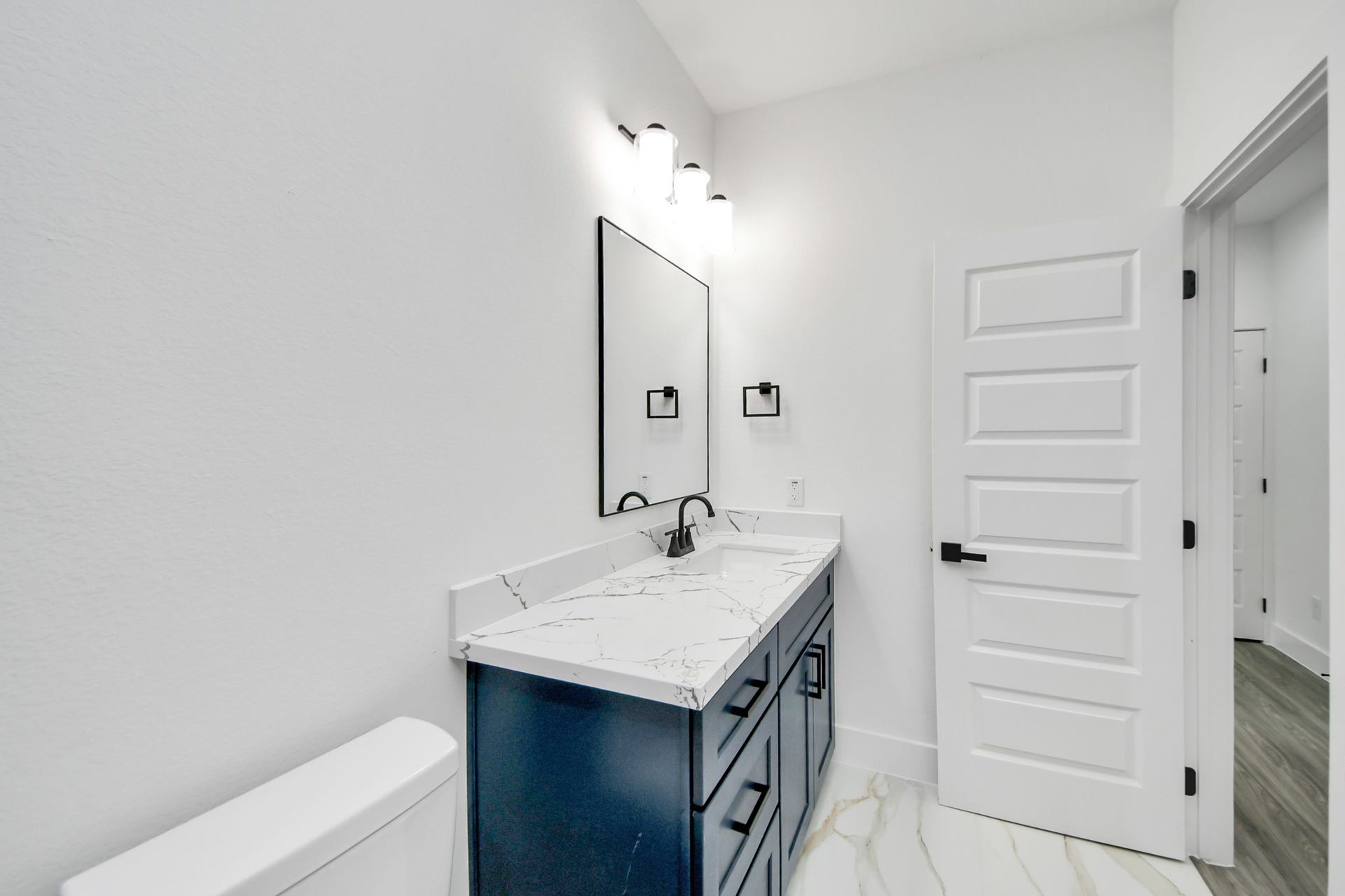 6707 Knox Street, Houston, TX 77091 Sleek bathroom featuring a chic navy vanity with elegant marble countertop, complemented by modern fixtures and bright lighting.