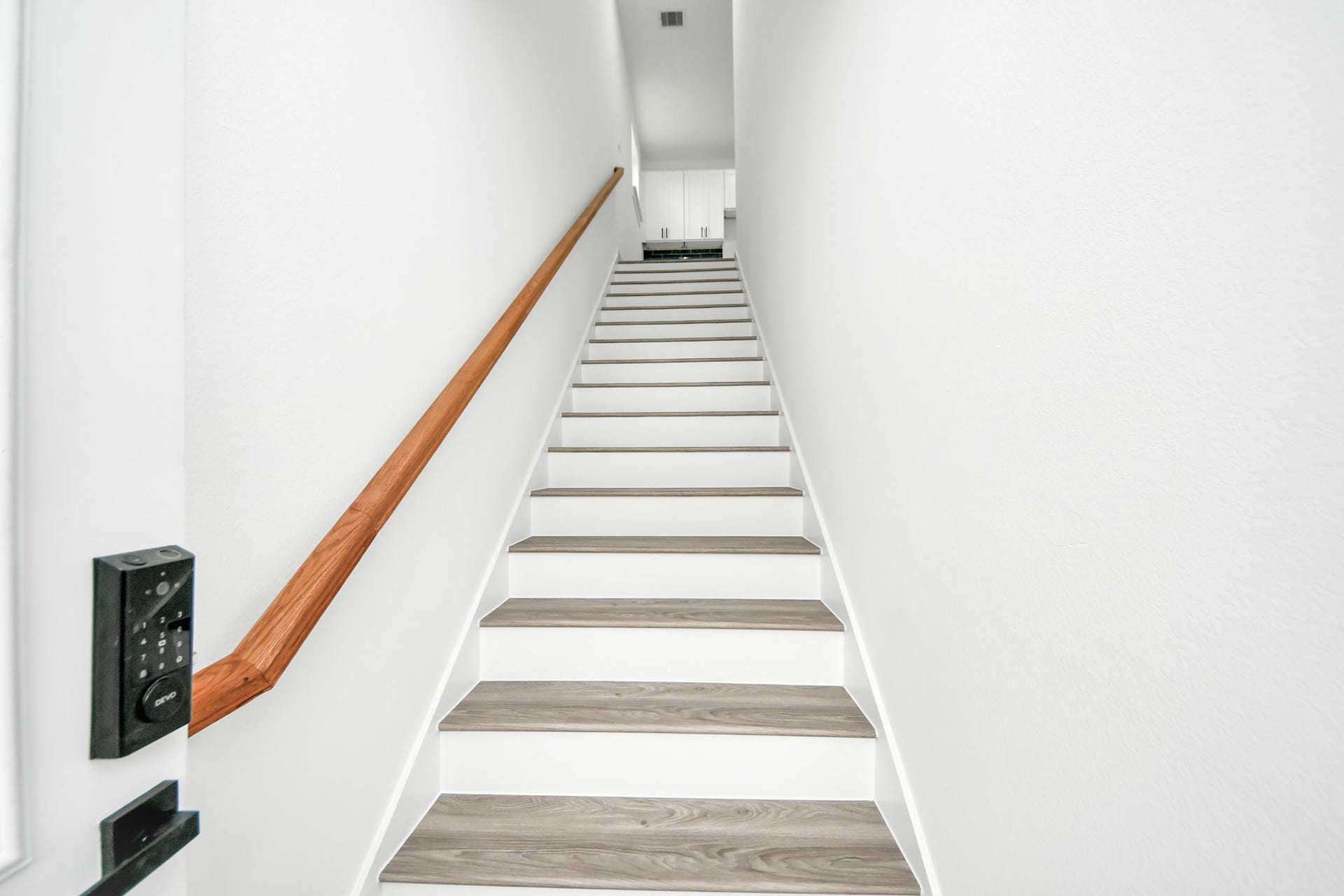 6707 Knox Street, Houston, TX 77091 Bright and inviting staircase with modern wood accents leads to the upper level, offering a glimpse of sleek cabinetry at the top.