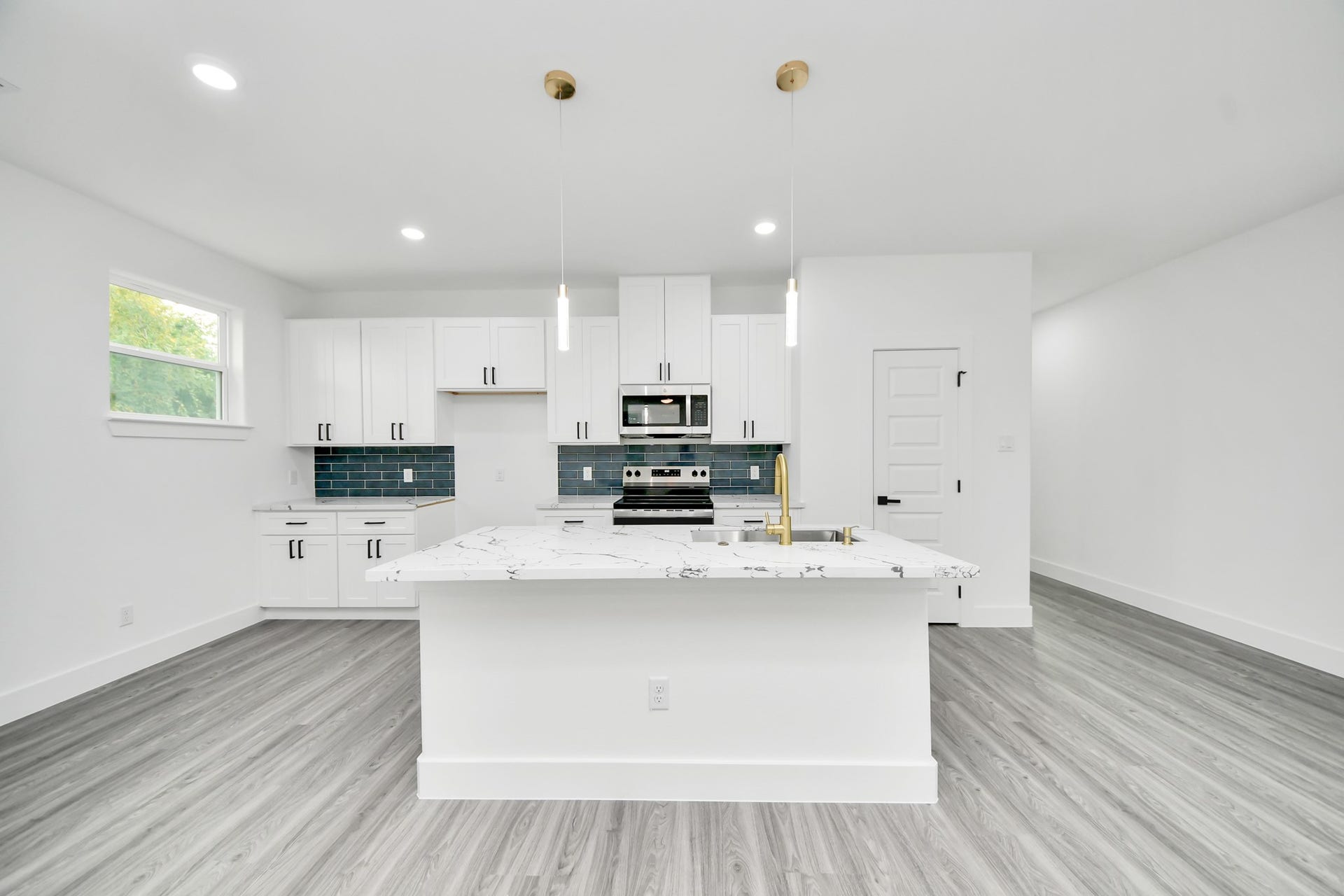6707 Knox Street, Houston, TX 77091 Sleek modern kitchen featuring a spacious island with marble countertops, stainless steel appliances, and elegant pendant lighting. The white cabinetry and stylish blue backsplash add a touch of sophistication.