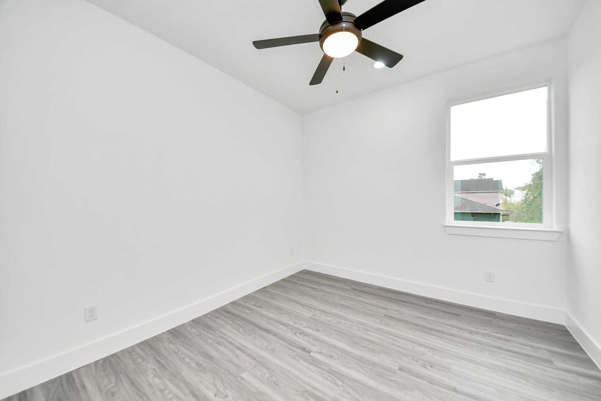 6707 Knox Street, Houston, TX 77091 Bright and airy bedroom featuring sleek laminate flooring, a modern ceiling fan, and a large window offering plenty of natural light.