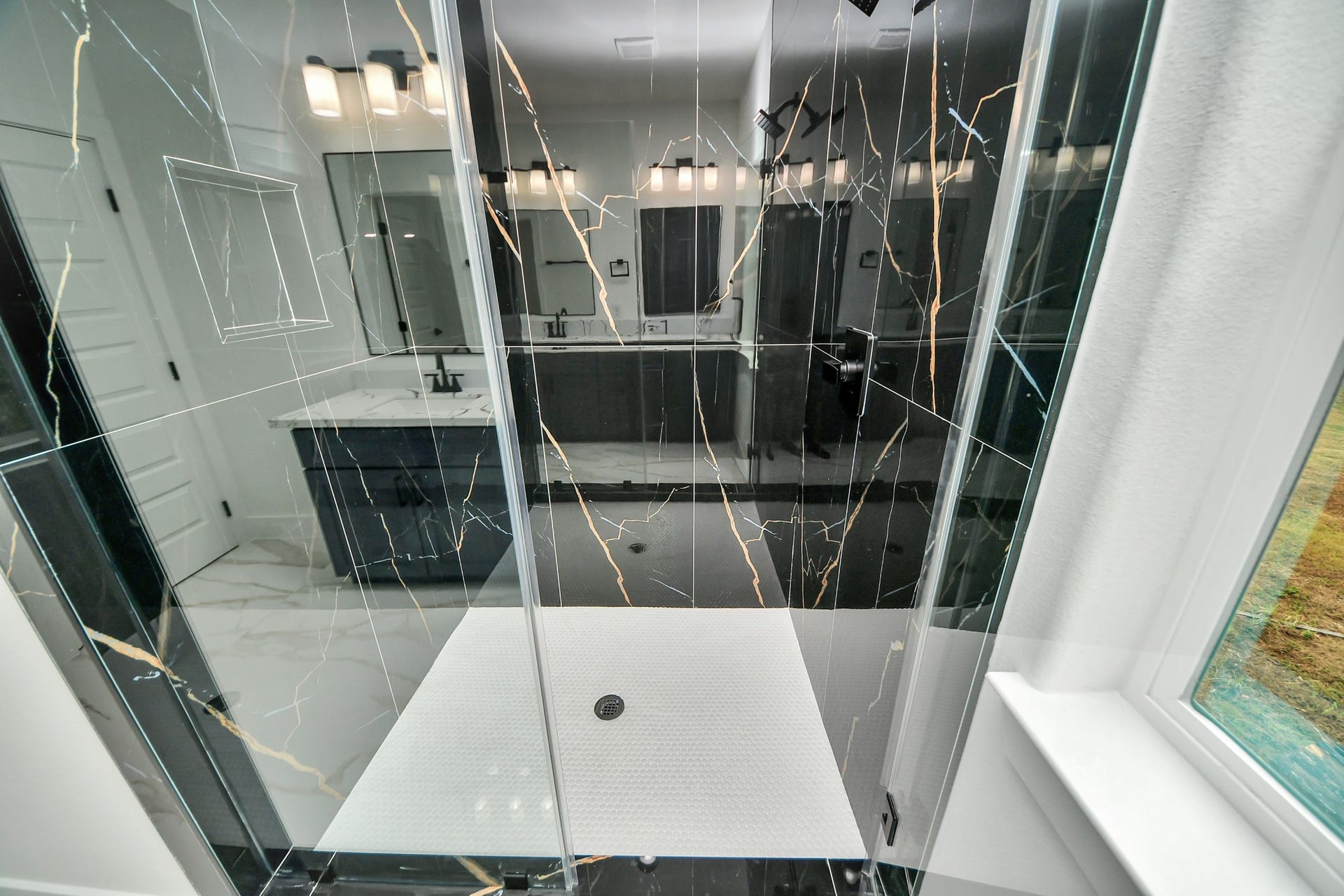 6707 Knox Street, Houston, TX 77091 Luxurious bathroom featuring a modern black marble shower with sleek glass doors and elegant fixtures, complemented by a bright vanity area.