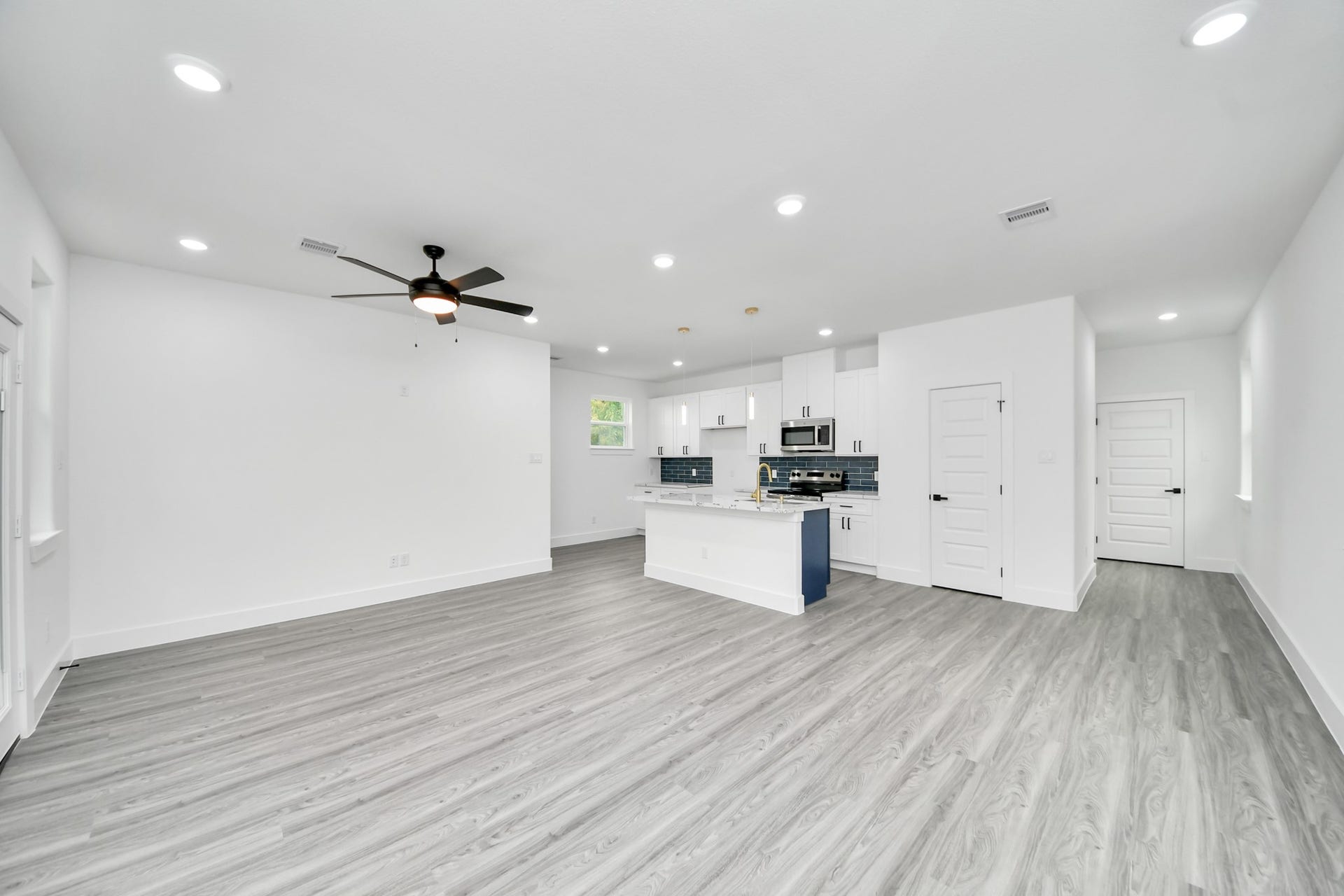 6707 Knox Street, Houston, TX 77091 Spacious open-concept living area with modern finishes, featuring sleek laminate flooring, recessed lighting, and a contemporary kitchen with an island and stainless steel appliances.