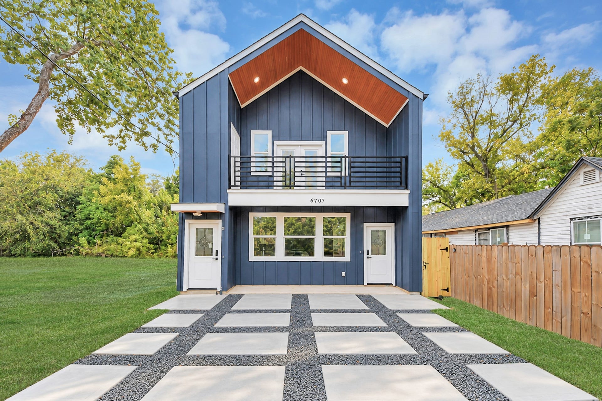 6707 Knox Street, Houston, TX 77091 Modern two-story home with a striking blue facade and clean lines, featuring a spacious balcony and a unique checkered driveway.