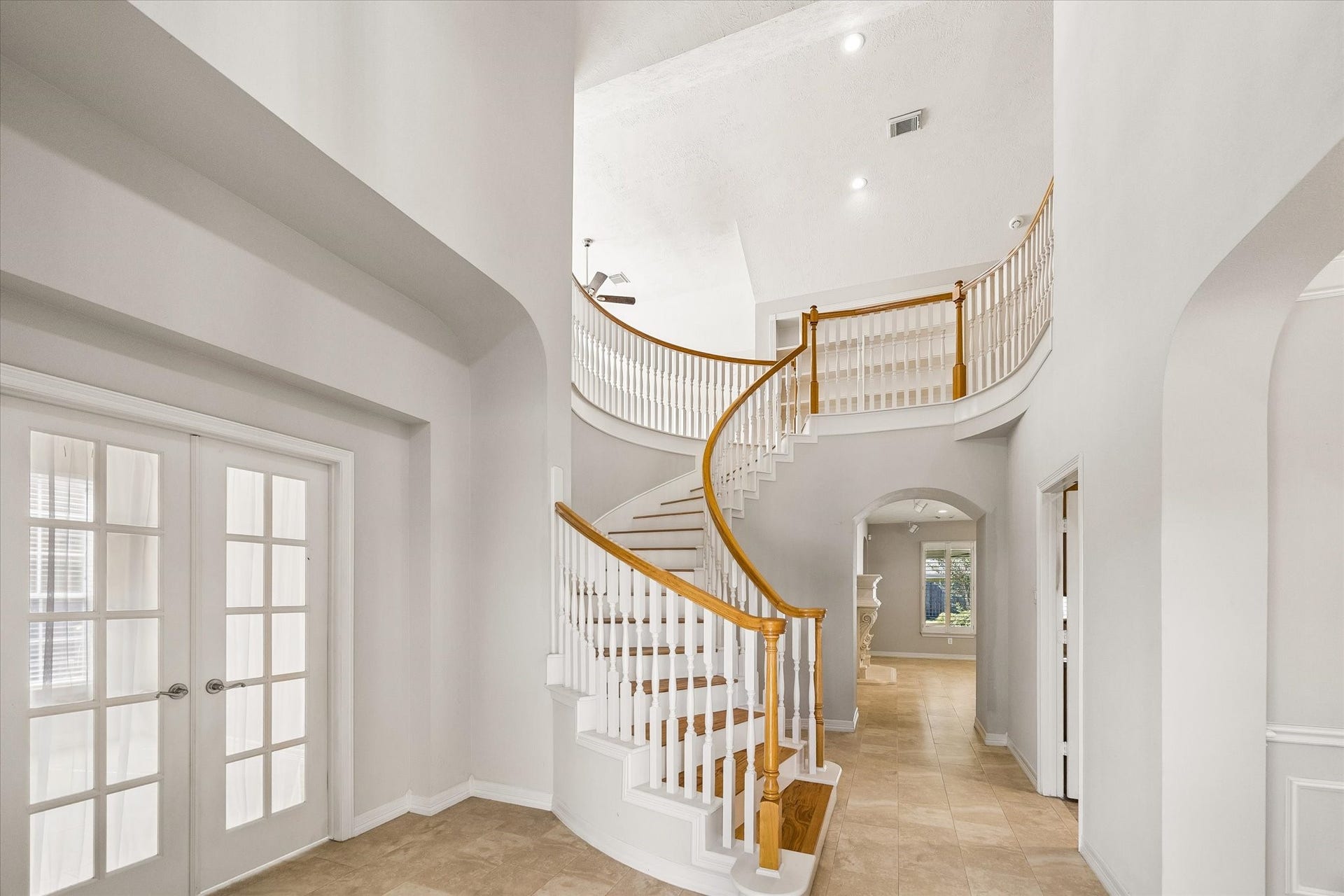 An impressive two story foyer with soaring ceilings, wrap around staircase, beautiful archways and trim detail. The study is to the left and formal dining is to the right.