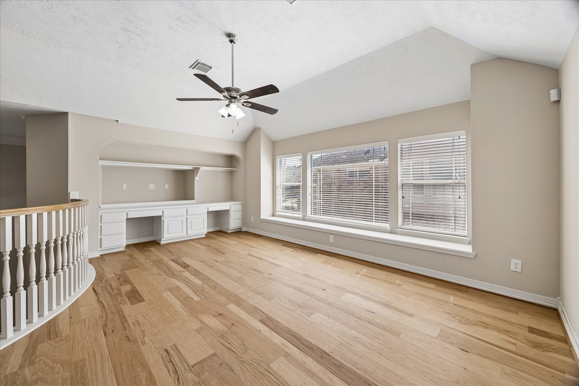 At the top of the stairs is this spacious game room/flex space with vaulted ceilings, built-ins and window bench seating, including additional built-in bookshelves at the top of the stairs between the game room and bedrooms.
