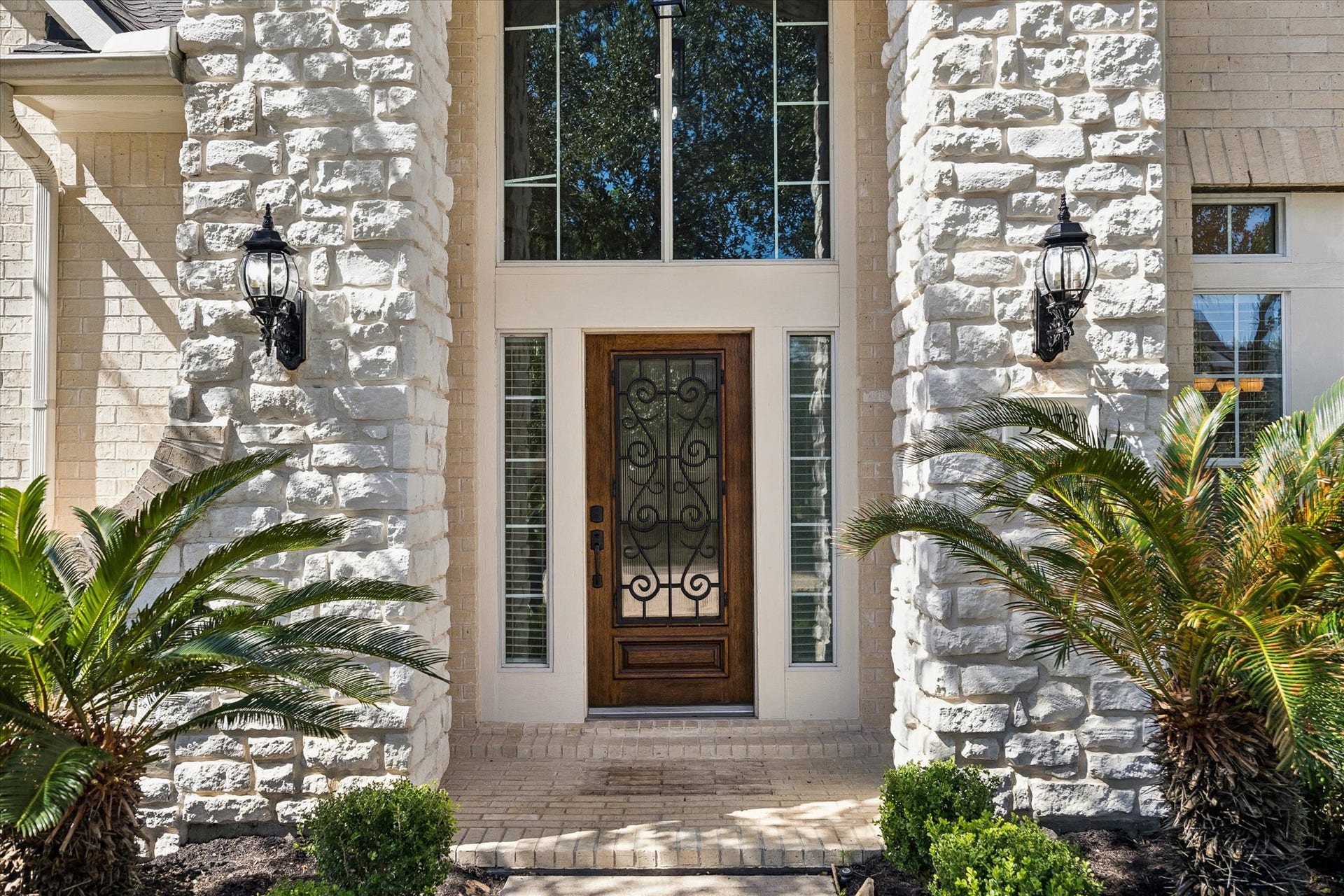 Welcoming entry with large arched window over the entry door and stone accents.