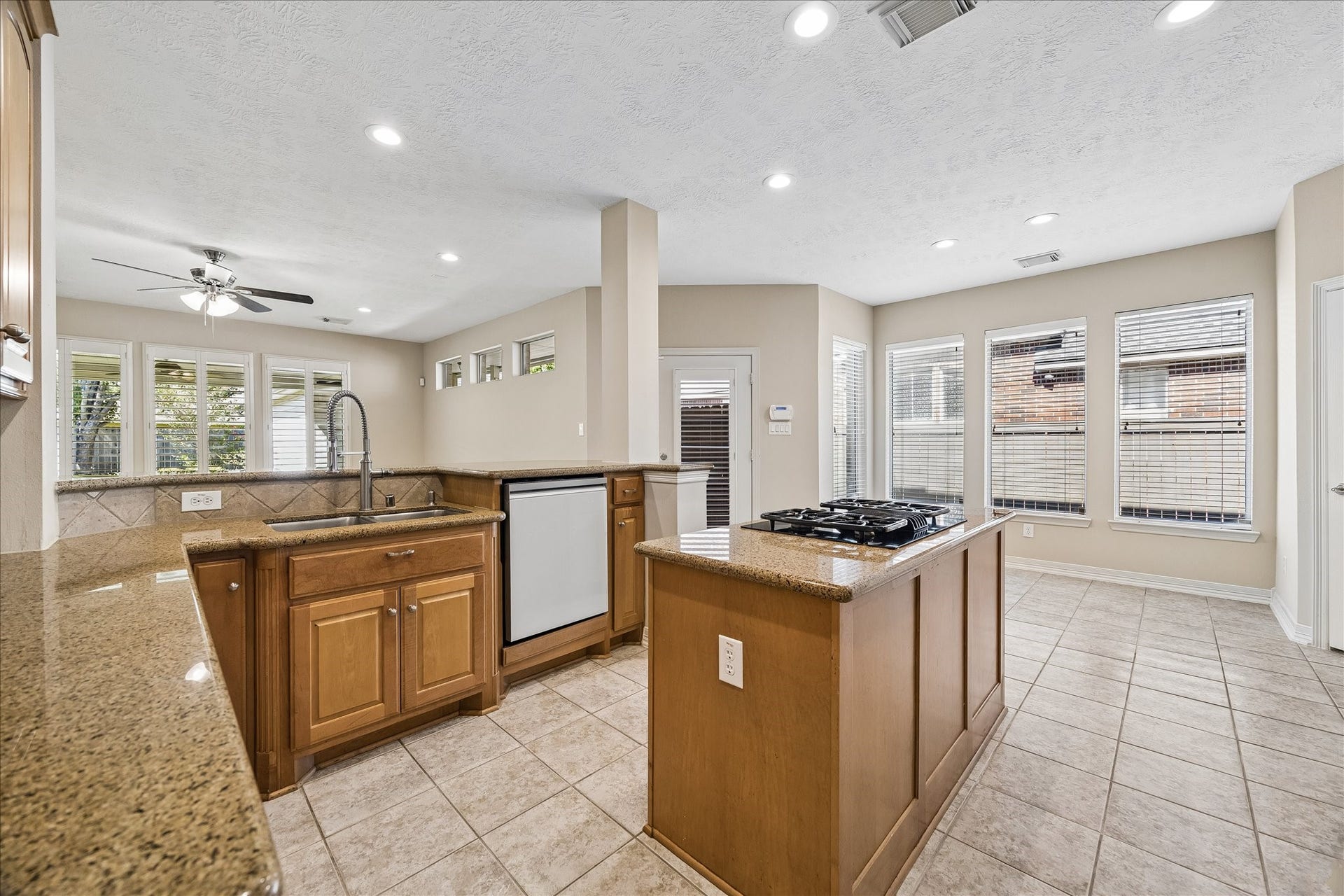 Island kitchen with warm cabinetry. There is plenty of cabinet space in this kitchen, those with glass uppers to the left can be used as a convenient butler's pantry to serve the connected dining room.