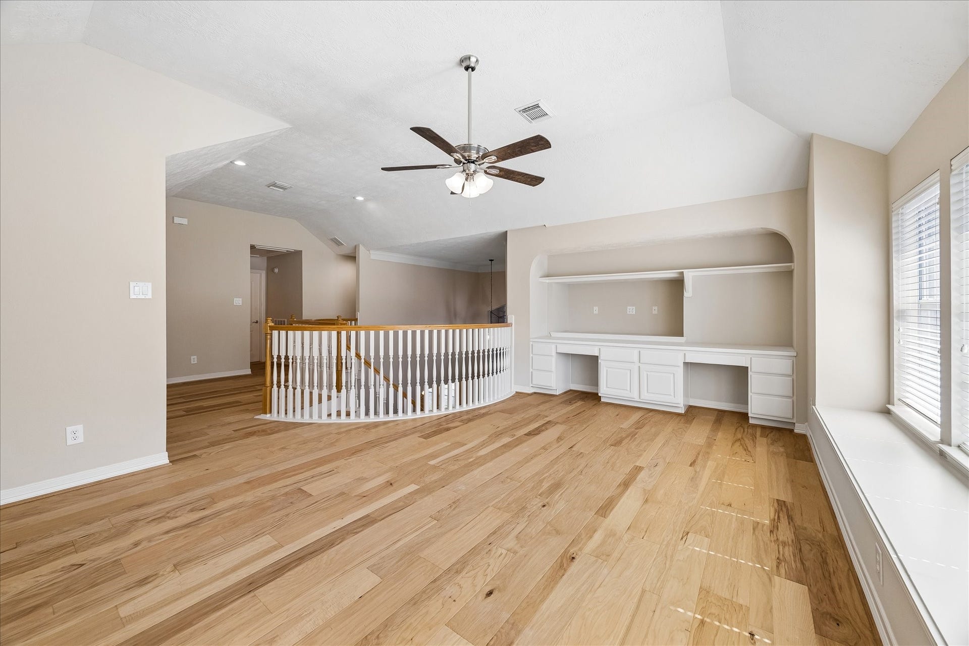 Oversized flex space at the upstairs landing features beautiful wood flooring and custom built-ins, creating a versatile area ideal for a secondary living space, study, or game room.