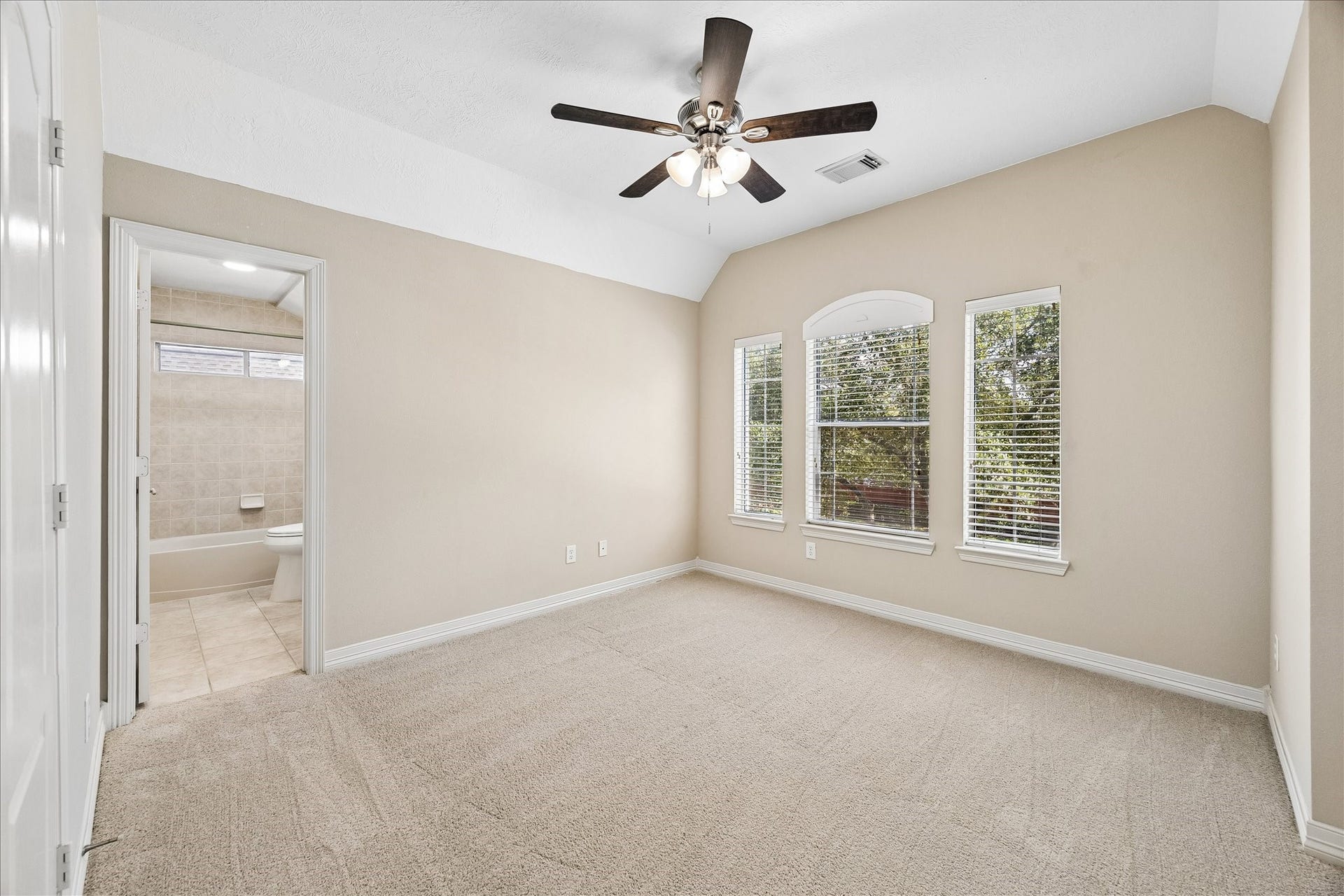 Vaulted ceiling, private ensuite & tree-lined views complete this secondary bedroom. The private bath makes it a perfect guest room.