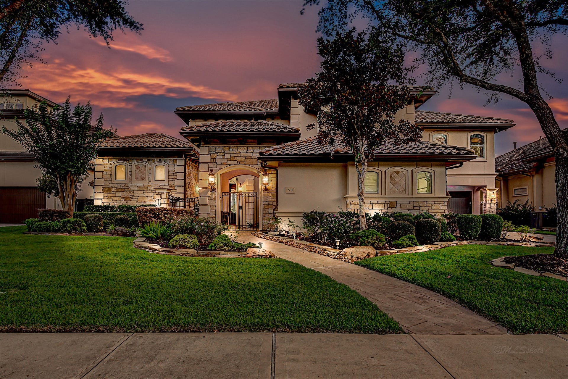 50 Sunset Park Lane, Sugar Land, TX 77479 This stunning home features a Mediterranean-style exterior with stone accents and a beautifully landscaped front yard. The warm, inviting lighting highlights the elegant architecture, while the well-maintained pathway leads to a charming entrance. Perfect for buyers seeking luxury and curb appeal.