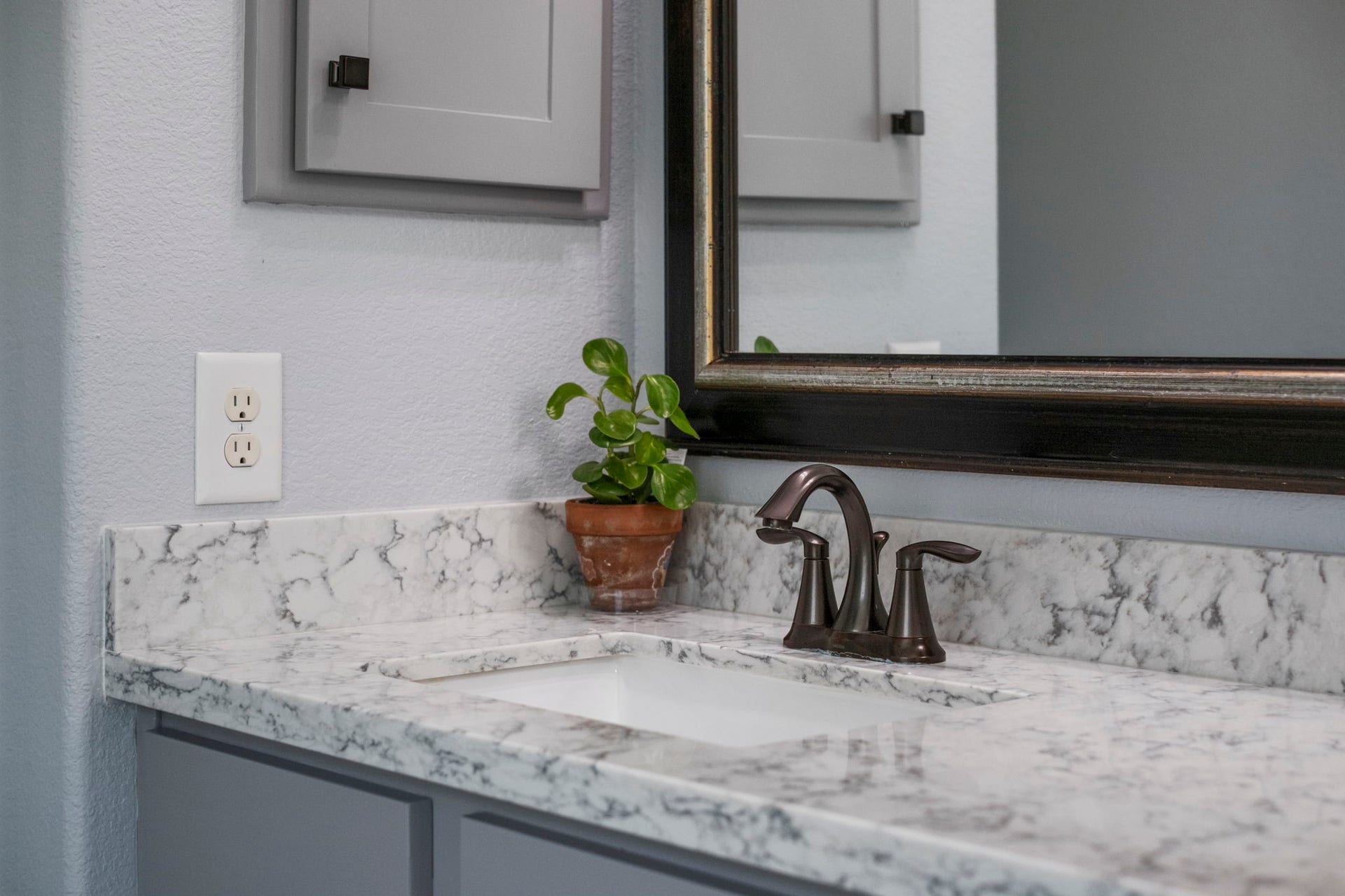19519 Arbor Lodge Drive, Cypress, TX 77433 The primary bathroom features a sleek countertop with two under-mounted sinks and elegant bronze faucets.
