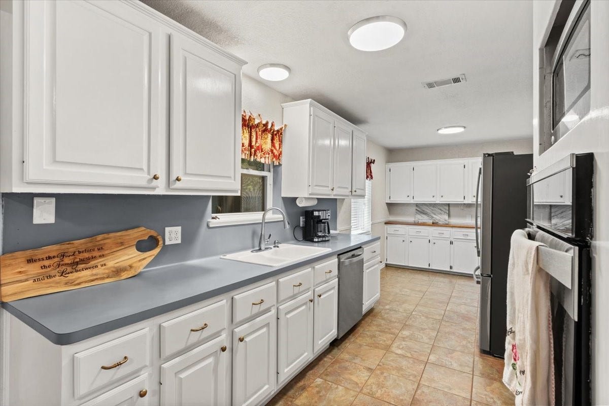 1209 E Brown Lane, Deer Park, TX 77536 Spacious kitchen with sleek white cabinetry with ample counter space, perfect for culinary enthusiasts.
