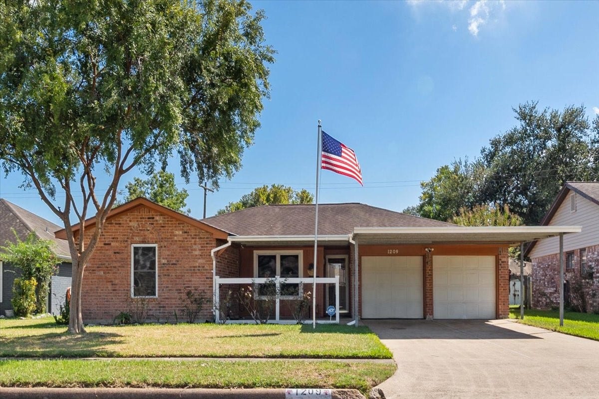 1209 E Brown Lane, Deer Park, TX 77536 Charming brick home with a welcoming front porch, mature tree, and attached garage, nestled in a serene neighborhood setting.