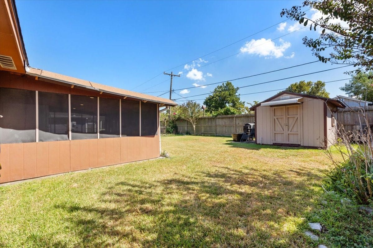 1209 E Brown Lane, Deer Park, TX 77536 Spacious backyard featuring a screened patio and a convenient storage shed with 30 amp electrical, ideal for outdoor enjoyment and organization.