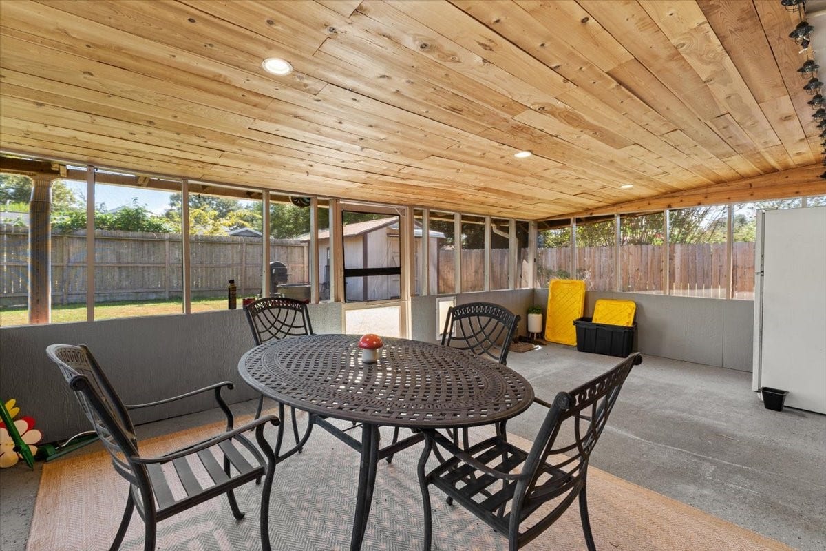 1209 E Brown Lane, Deer Park, TX 77536 Spacious screened-in patio with a wood-paneled ceiling, perfect for outdoor dining and relaxation, overlooking a private fenced backyard.
