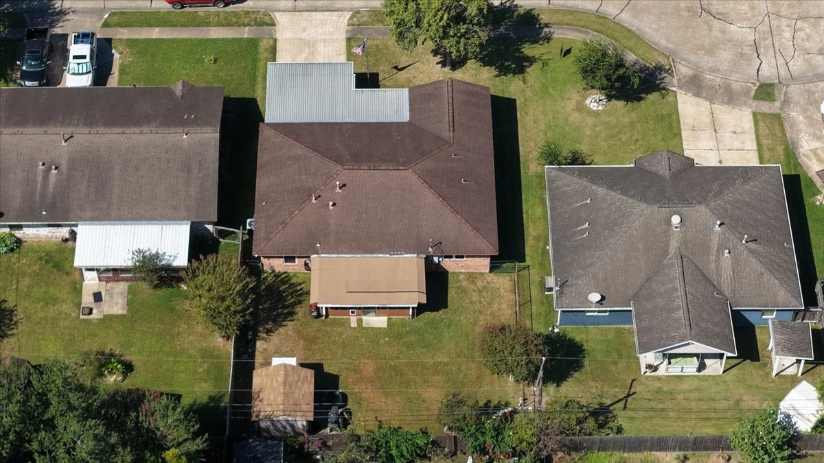 1209 E Brown Lane, Deer Park, TX 77536 Aerial view of single-story home with a spacious backyard. The property features a well-maintained lawn, a cozy patio area, and a convenient driveway. Ideal for those seeking a peaceful suburban setting.
