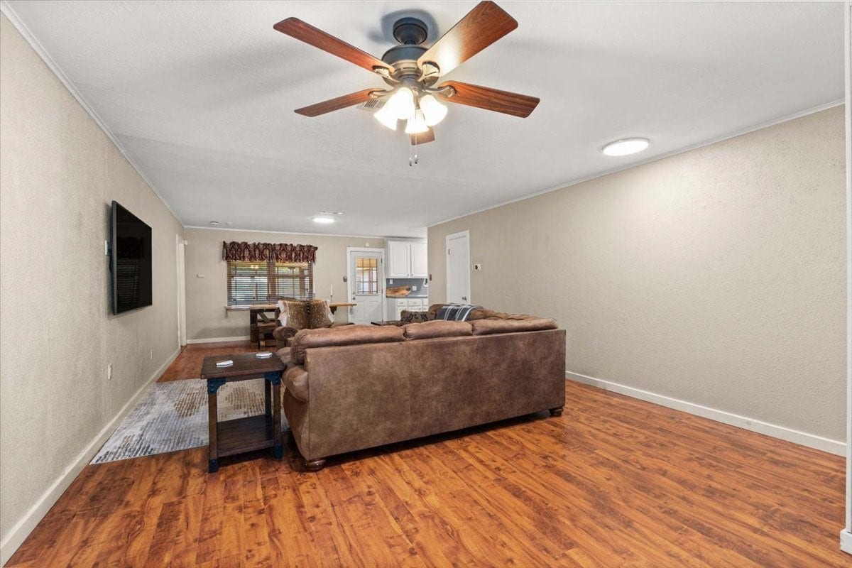 1209 E Brown Lane, Deer Park, TX 77536 Spacious living area with warm wood flooring, new ceiling fan, seamlessly leading to the dining and kitchen spaces.