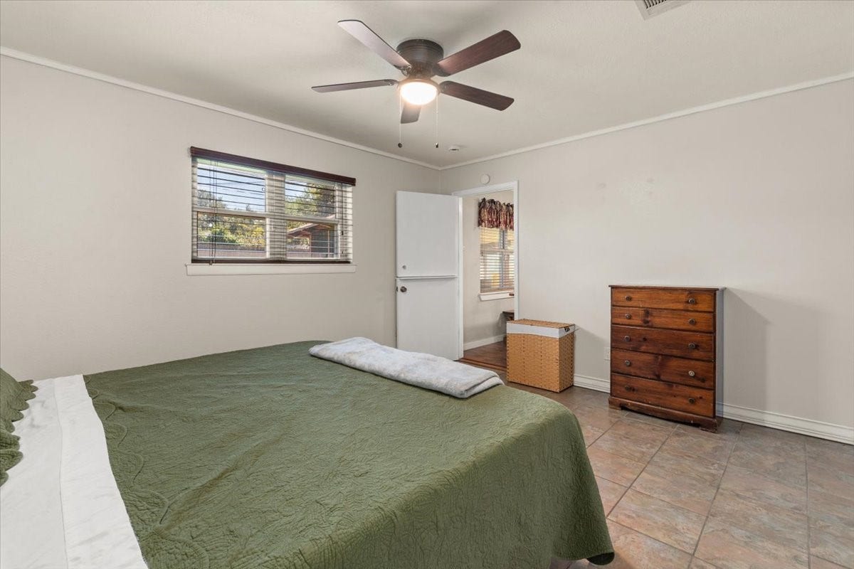 1209 E Brown Lane, Deer Park, TX 77536 Spacious primary bedroom with neutral tones, featuring a new ceiling fan and tiled flooring for a comfortable and inviting atmosphere.
