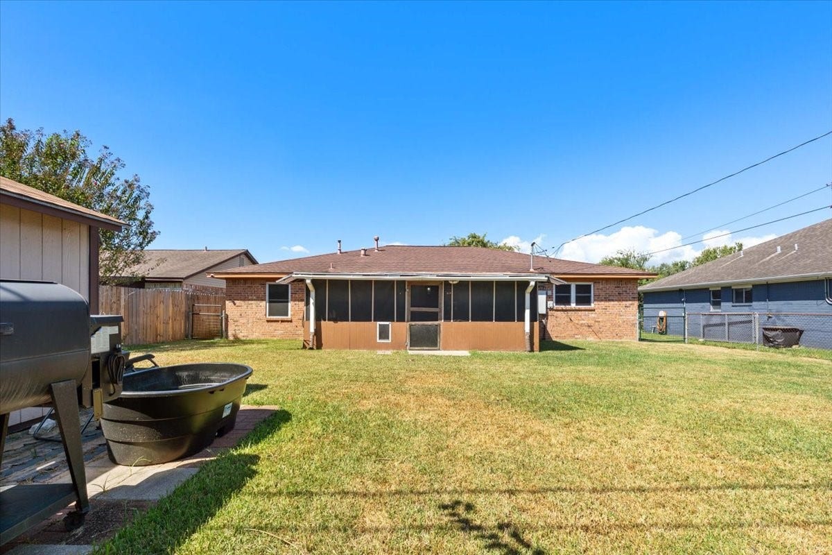 1209 E Brown Lane, Deer Park, TX 77536 Spacious backyard with a screened porch and lush lawn, perfect for outdoor gatherings and relaxation.
