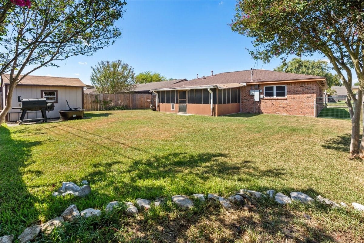 1209 E Brown Lane, Deer Park, TX 77536 Charming backyard with a spacious lawn, mature trees, and a screened patio perfect for outdoor entertaining. A storage shed adds convenience, while a privacy fence ensures a tranquil setting.
