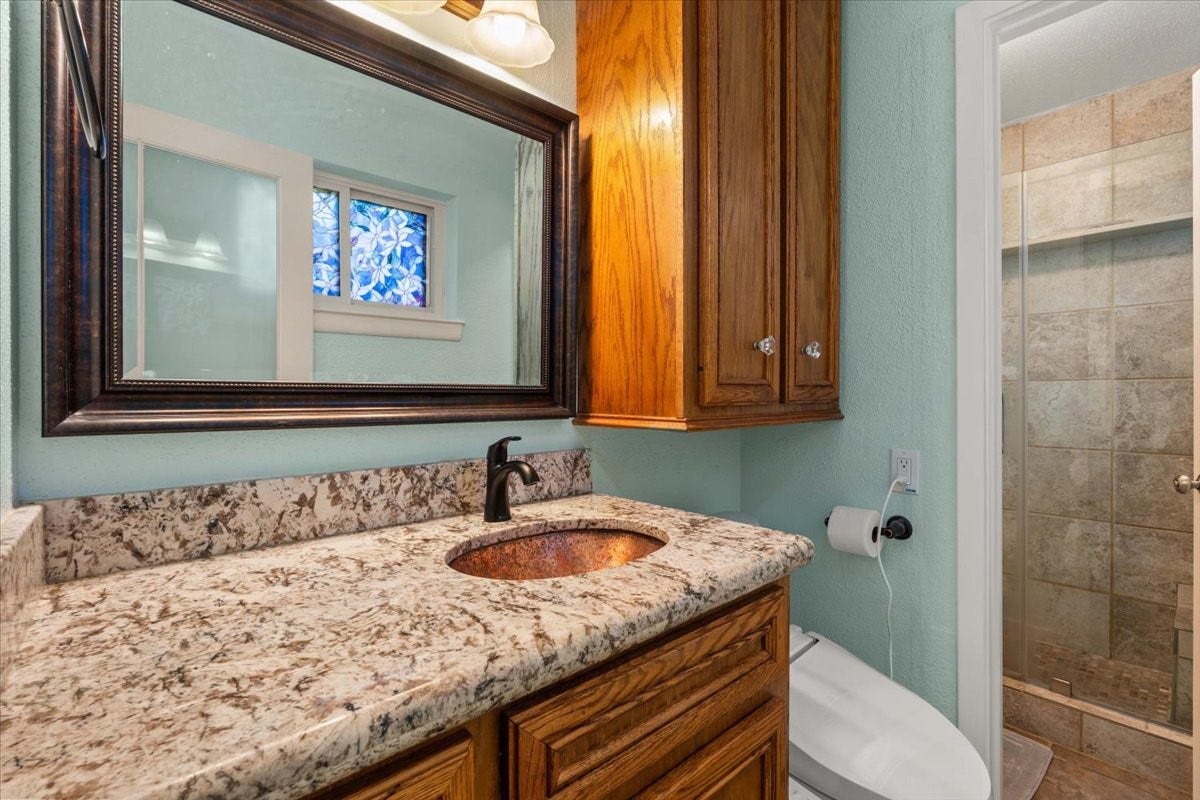 1209 E Brown Lane, Deer Park, TX 77536 Charming bathroom featuring a granite countertop, elegant wood cabinetry, and a beautifully tiled shower. Hollywood bath
