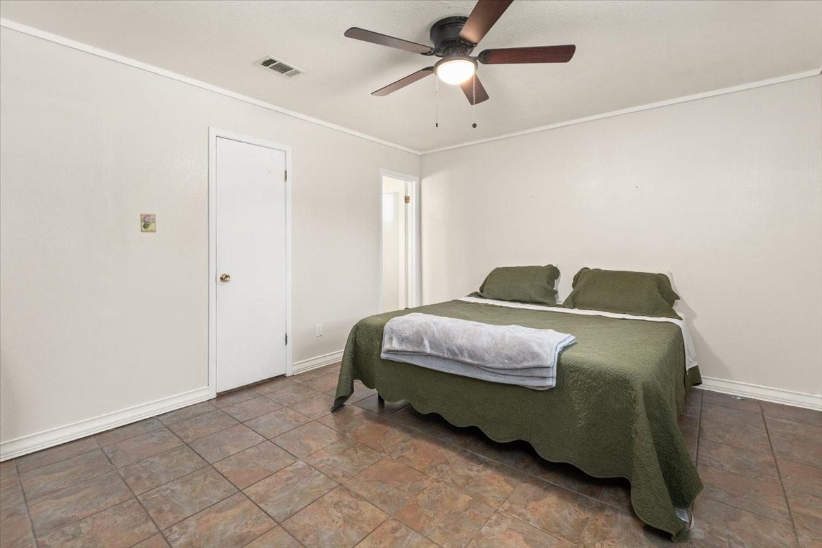 1209 E Brown Lane, Deer Park, TX 77536 Spacious primary bedroom with neutral tones, featuring a new ceiling fan and tiled flooring for a comfortable and inviting atmosphere.