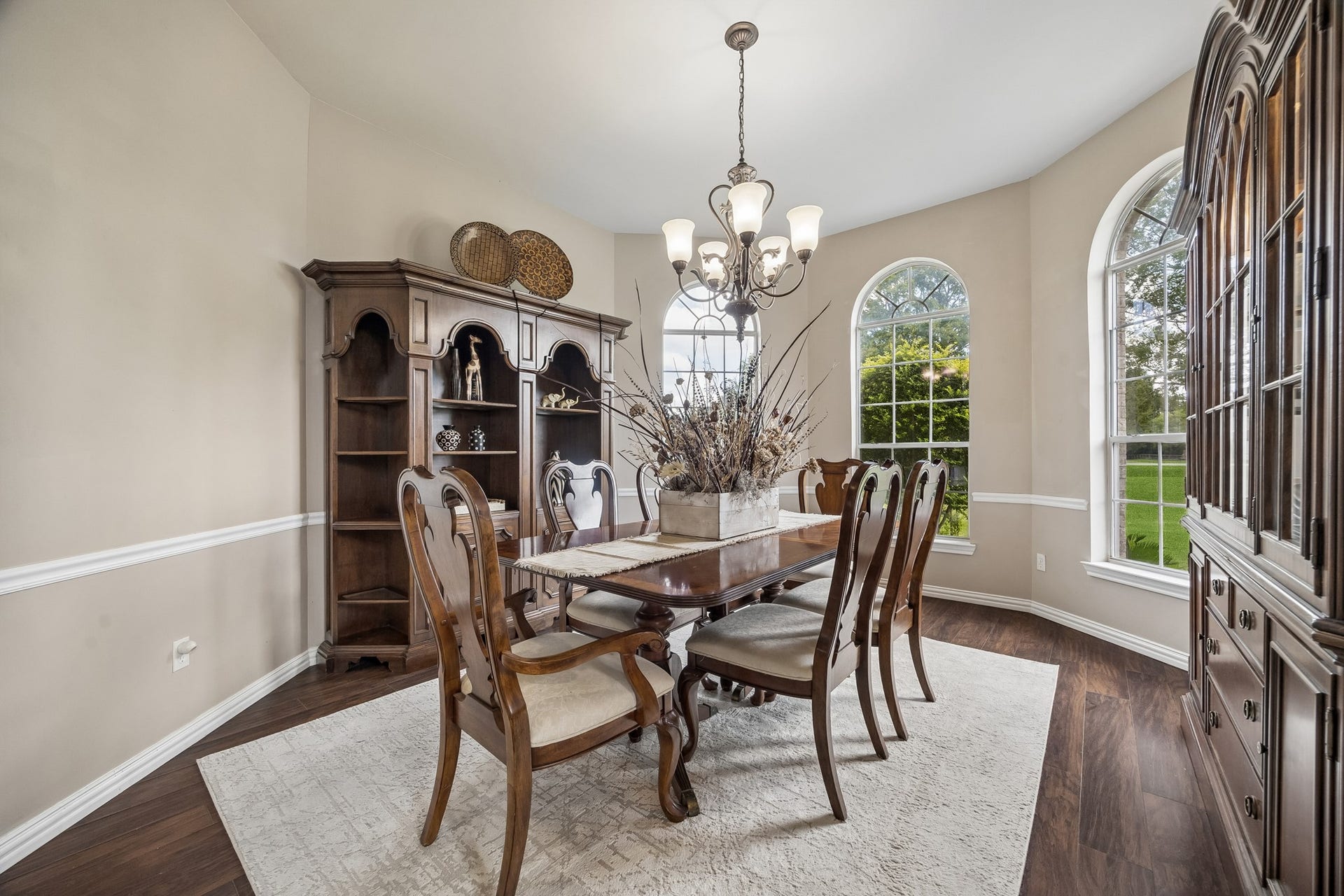 1319 Brazoswood Place, Richmond, TX 77406 This elegant 15x13 formal dining room features graceful arched windows, rich hardwood flooring, and a statement chandelier.